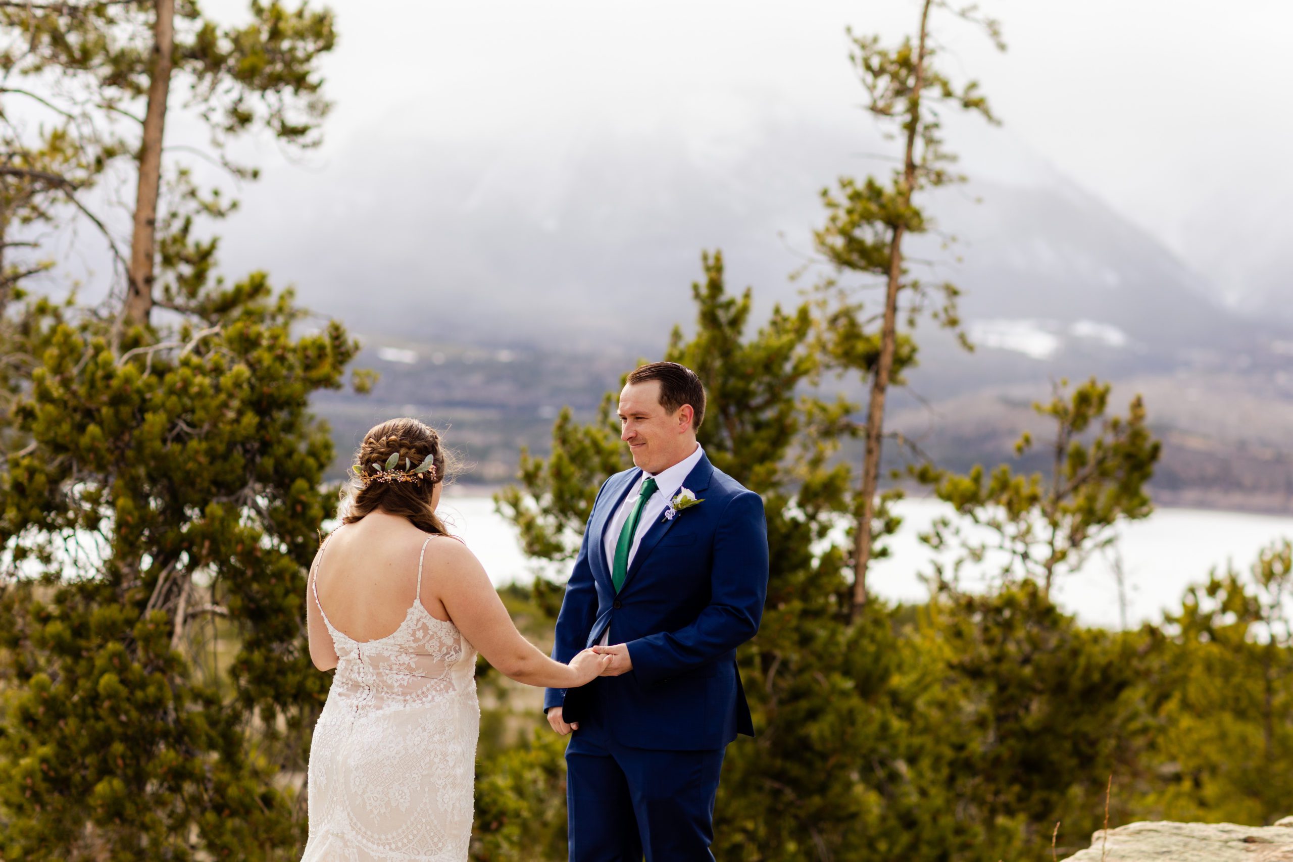 The groom smiles at his bride while she reads her vows to him before their Sapphire Point Elopement.