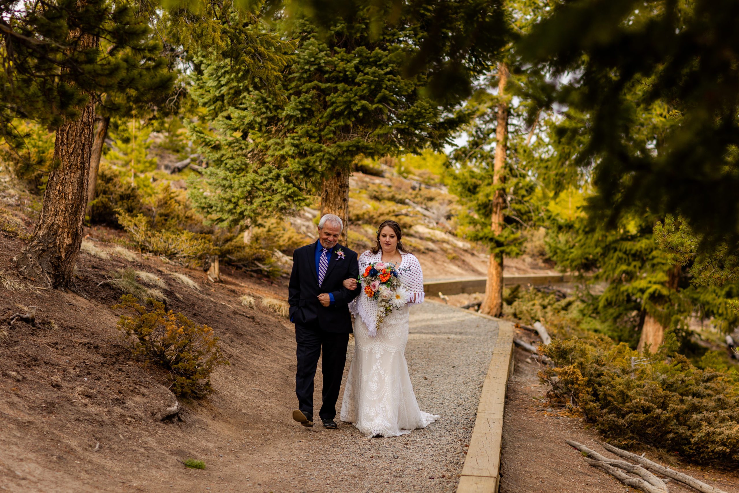 The bride walks down the aisle with her father at her Sapphire Point Elopement.
