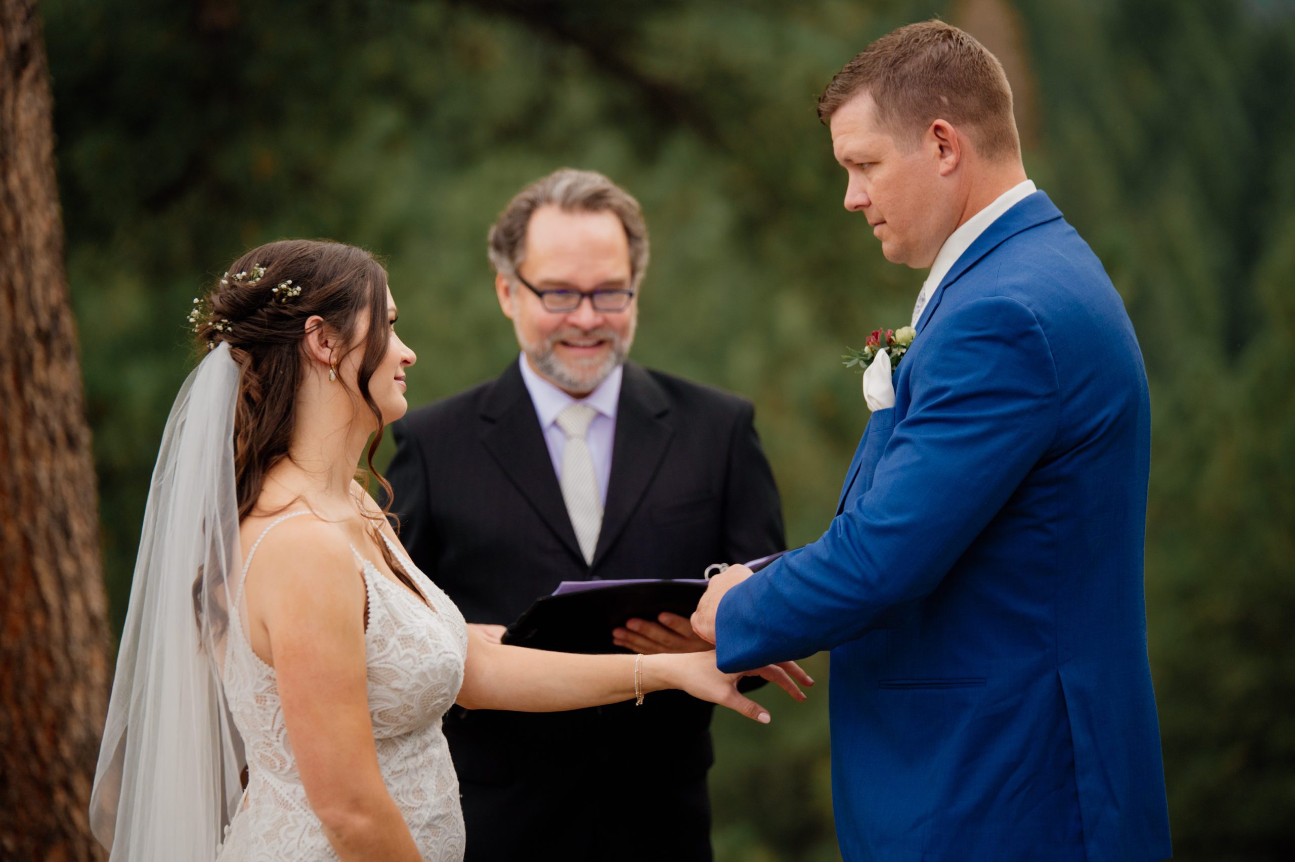 The groom places the ring on his bride's hand at their artist point elopement ceremony. 