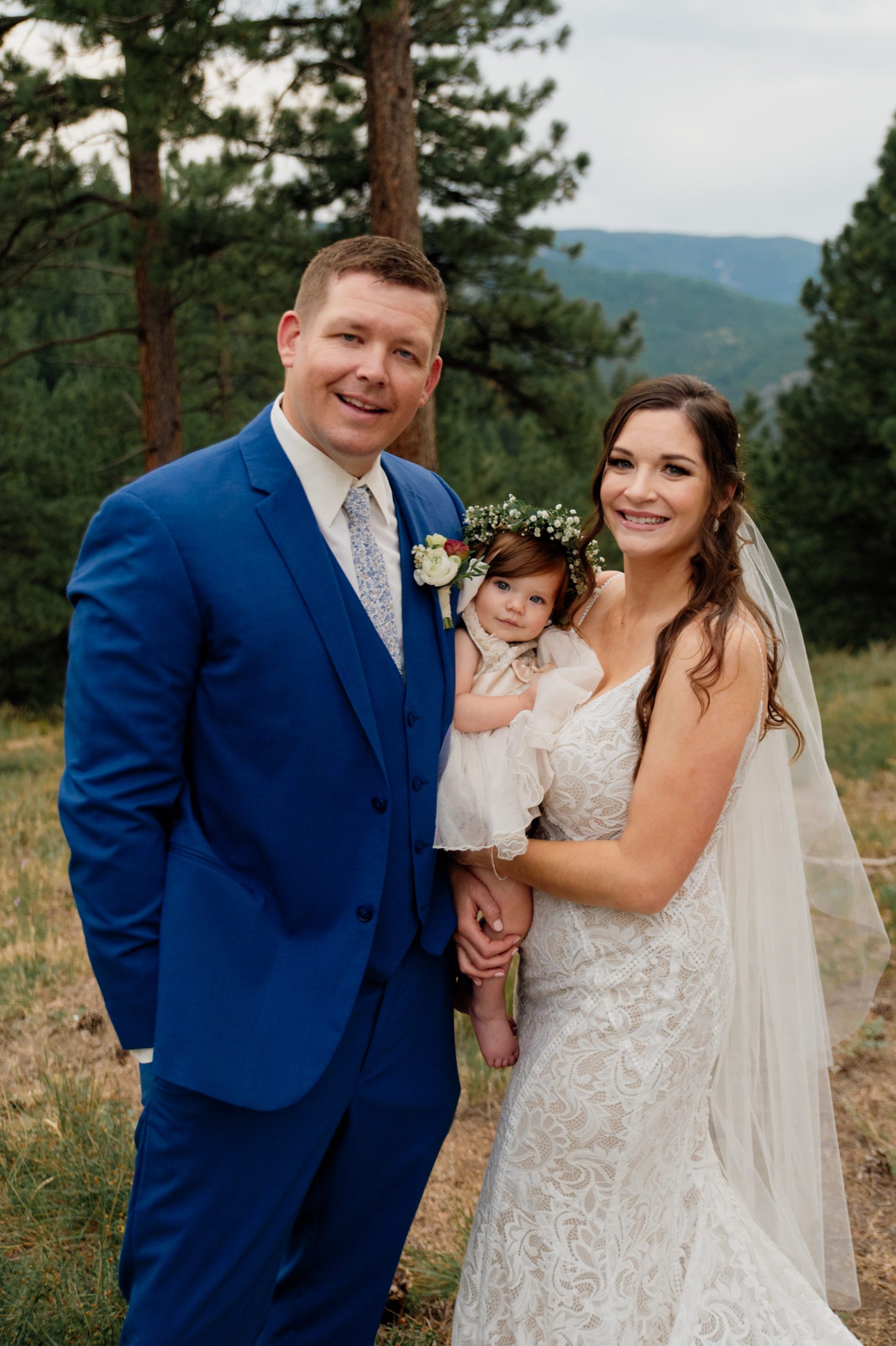 The bride and groom smile happily while holding their adorable baby girl after their ceremony at Artist Point. 