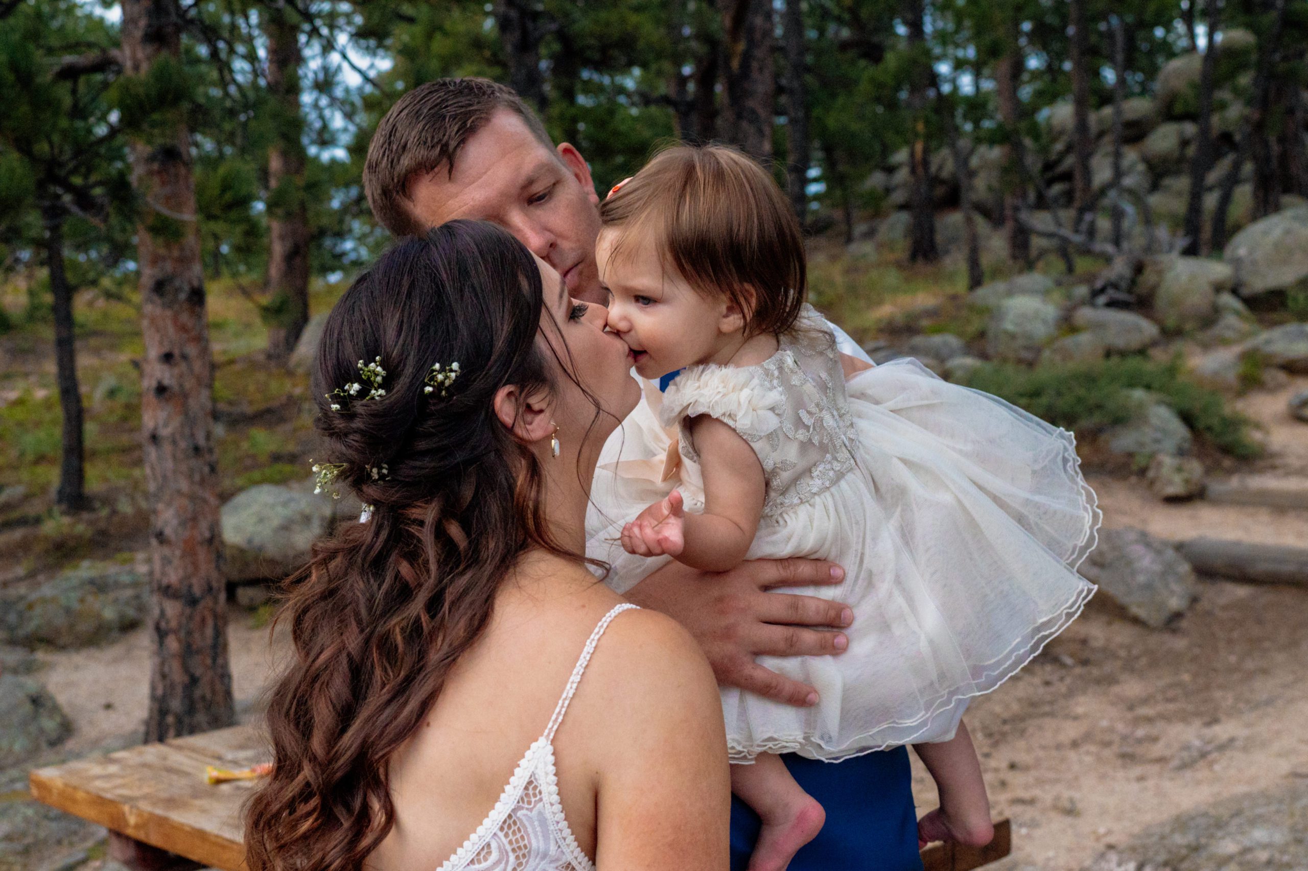The groom holding his little girl while his new bride kisses her sweetly on the lips after their Artist Point elopement. 