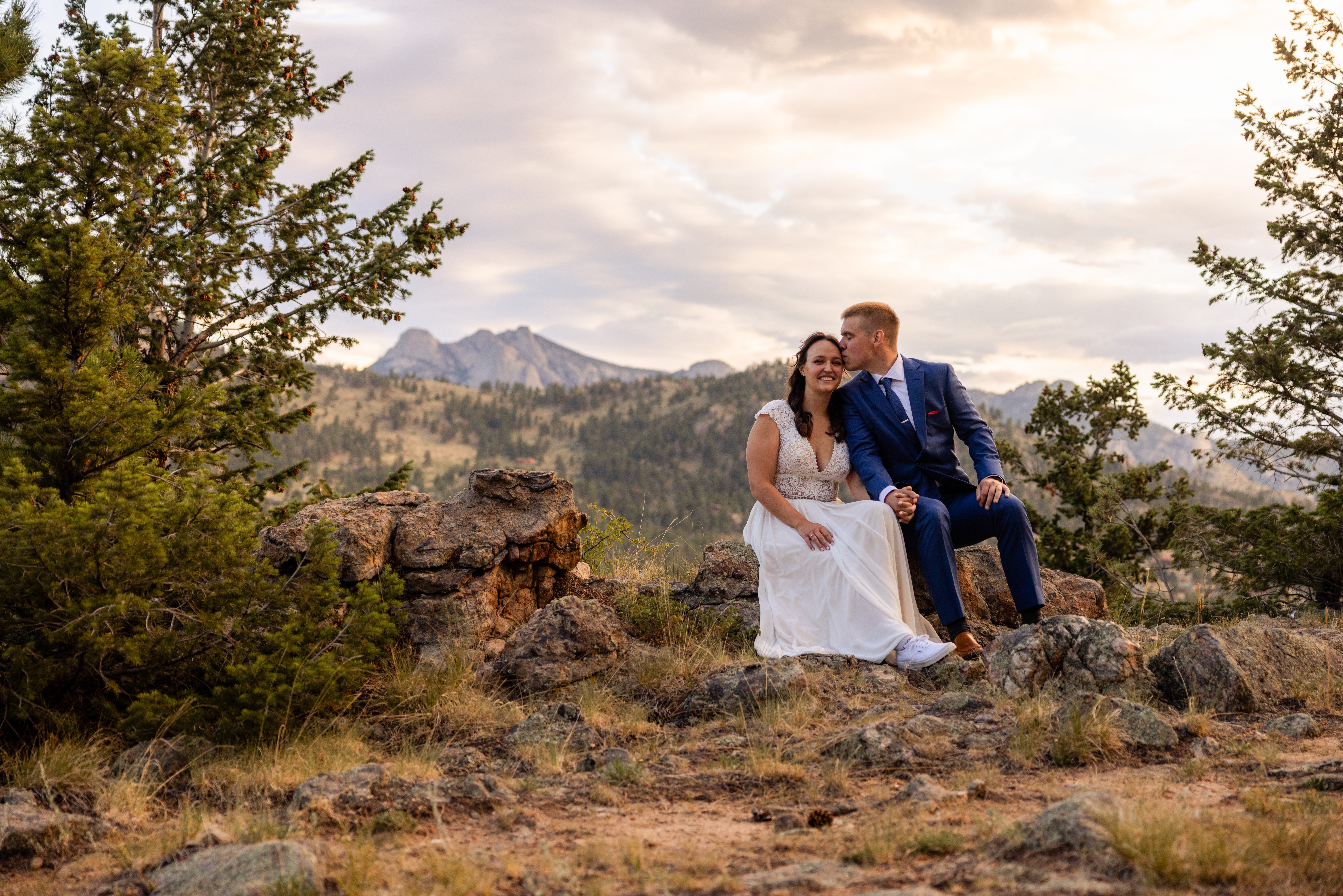 the groom kisses his bride on their wedding day during their portraits near Romantic RiverSong Inn in Estes Park.