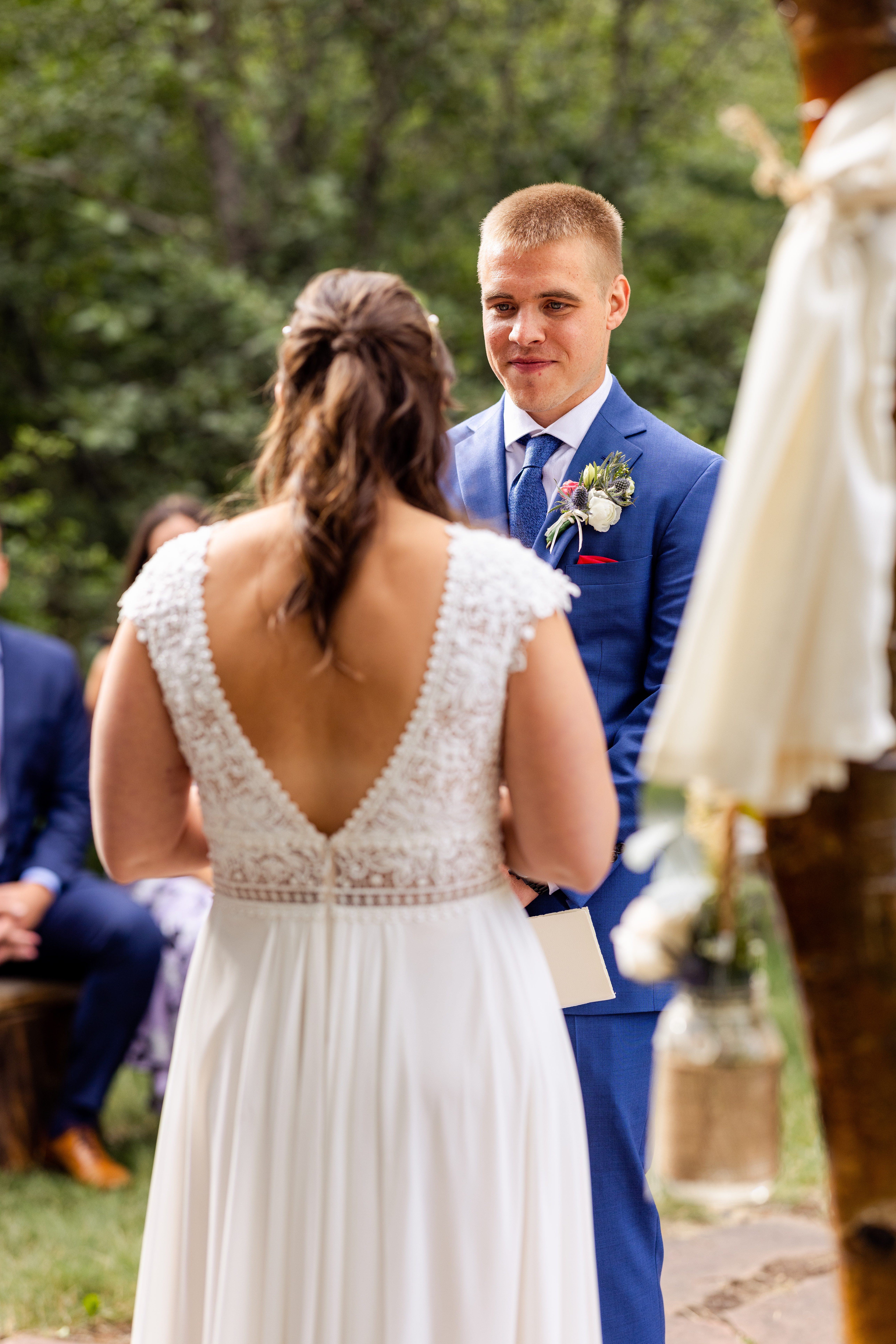 the groom looks at his bride as she shares her vows at Romantic RiverSong Inn in Estes Park during their wedding ceremony. 