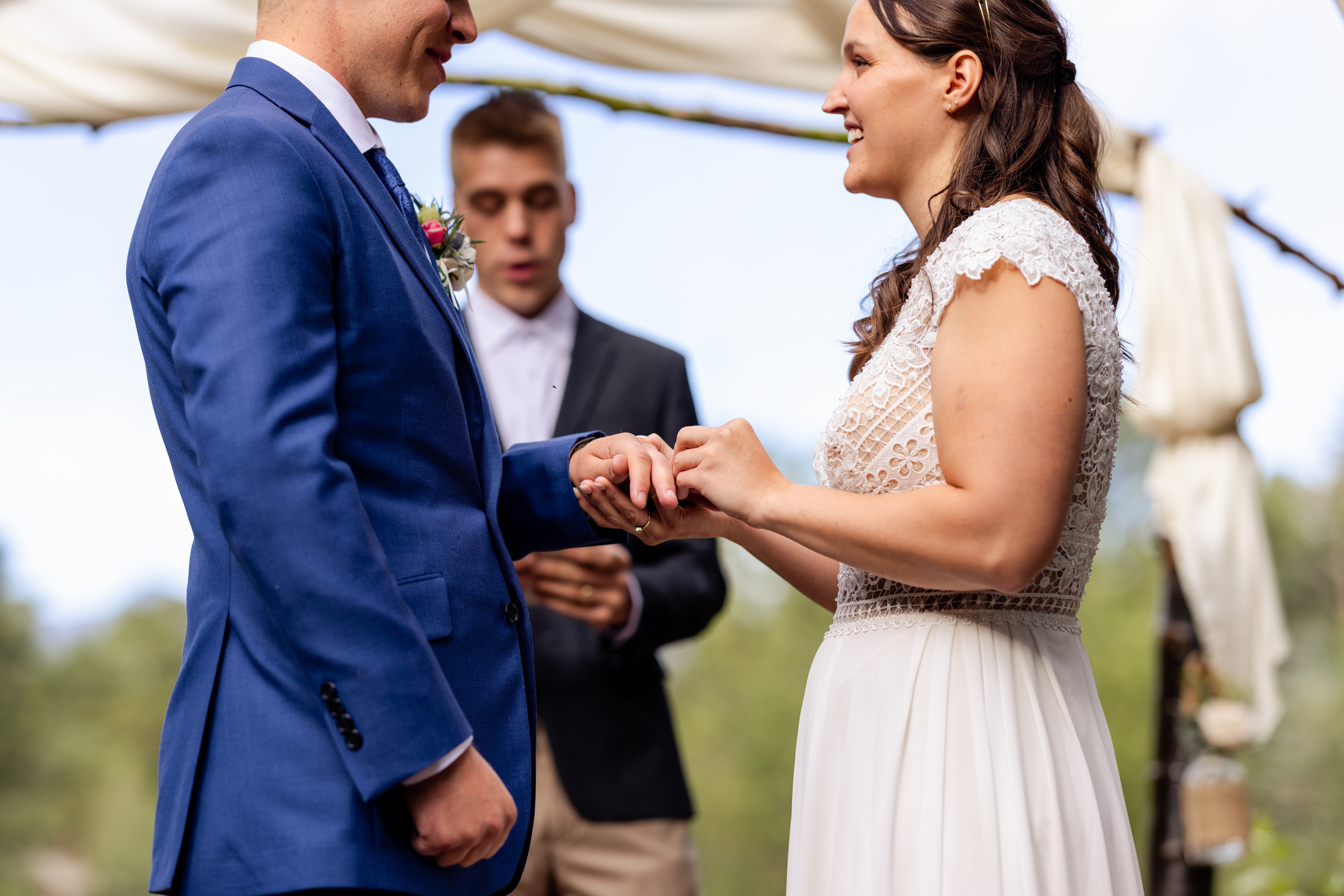 The bride places the ring on her grooms hand during their wedding ceremony at Romantic RiverSong Inn in Estes Park. 