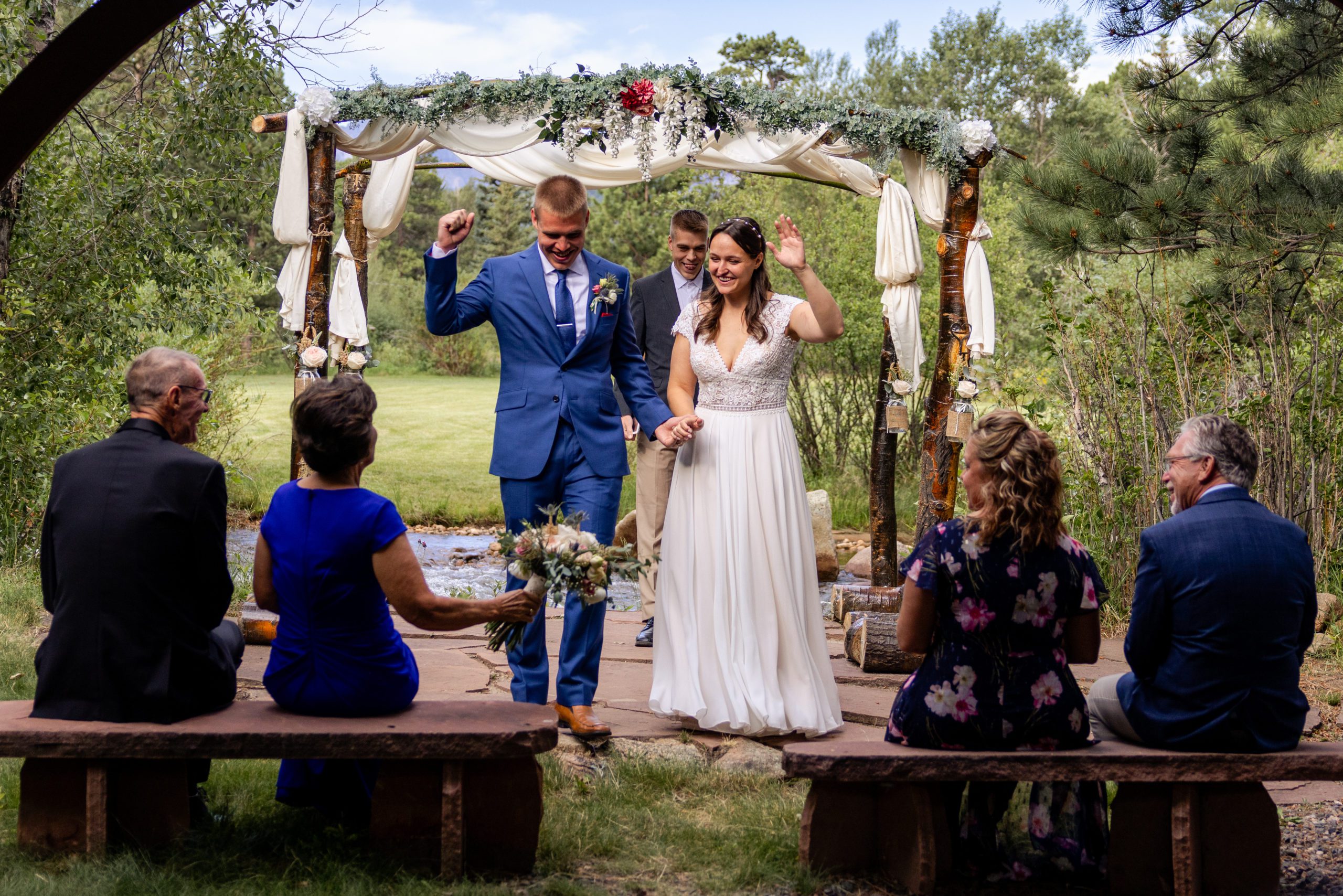 The bride and groom raise their hands in celebration of becoming husband and wife after their ceremony at Romantic RiverSong Inn in Estes Park.