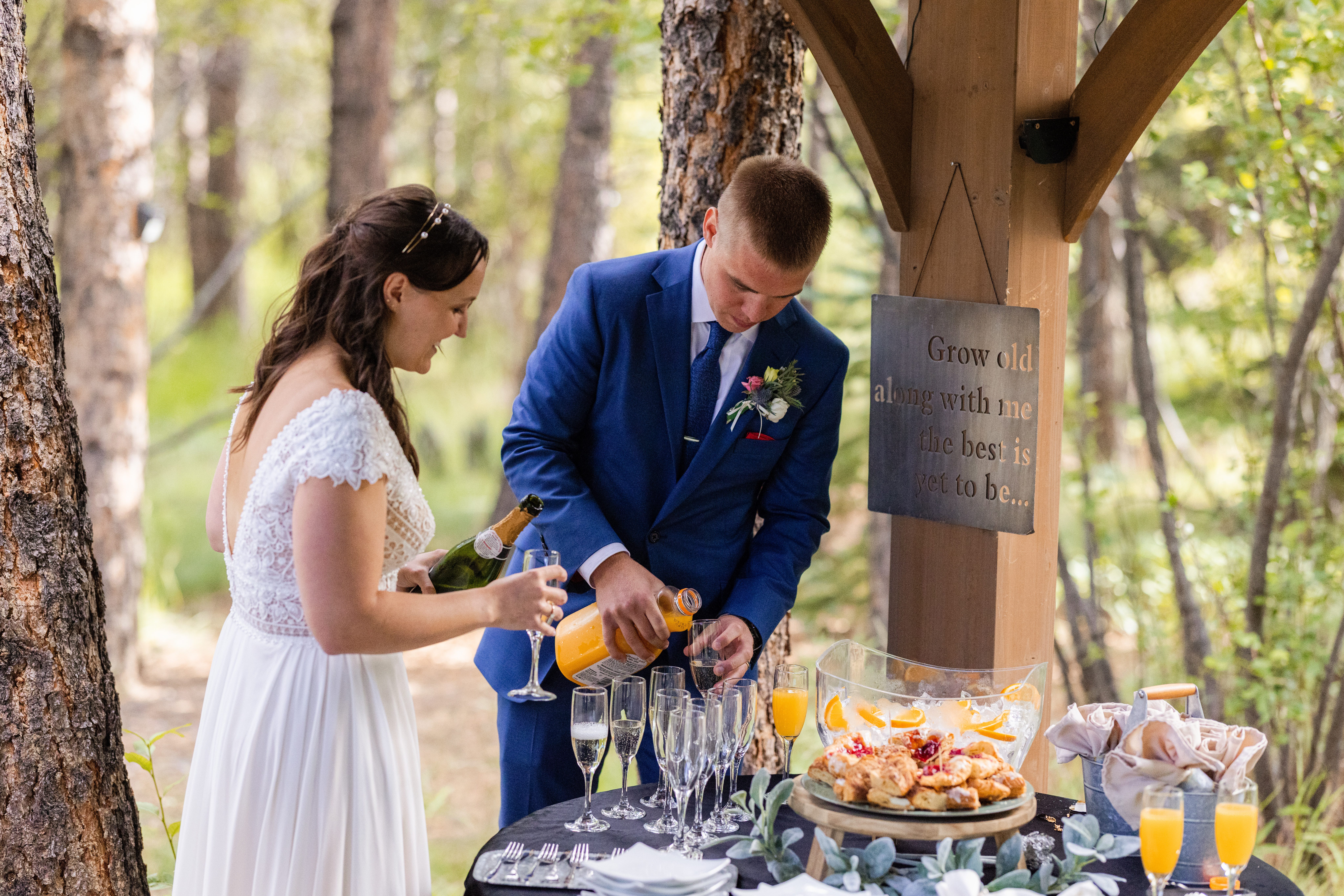 The groom making mimosas with his bride at their reception at Romantic RiverSong Inn in Estes Park. 