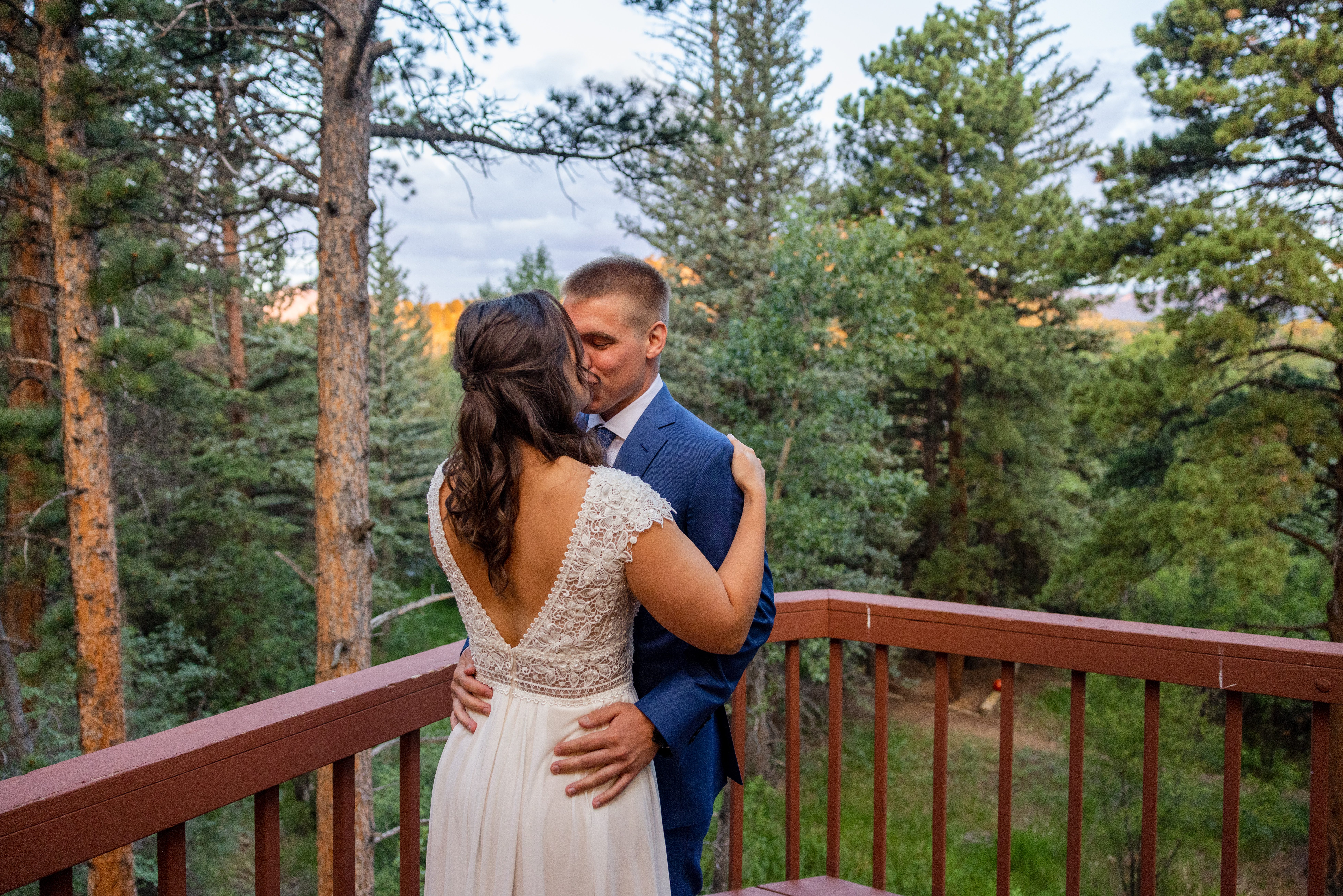 The groom kisses his bride after their first look at Romantic RiverSong Inn in Estes Park on their wedding day 