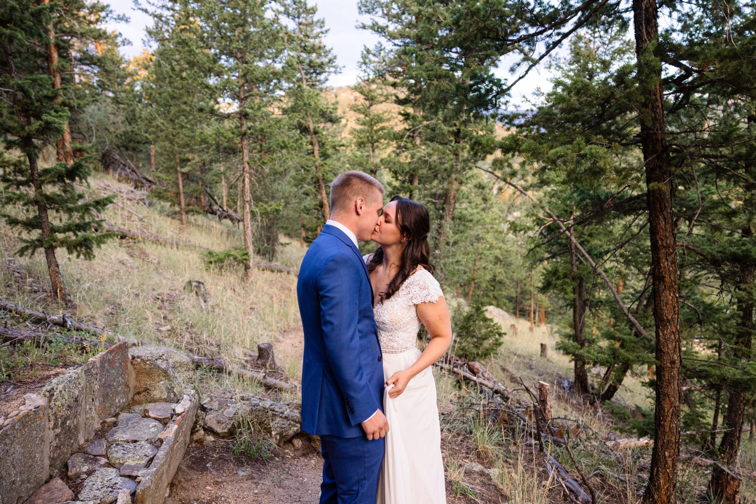 the bride kisses her groom on the trail at Romantic RiverSong Inn in Estes Park on their wedding day 