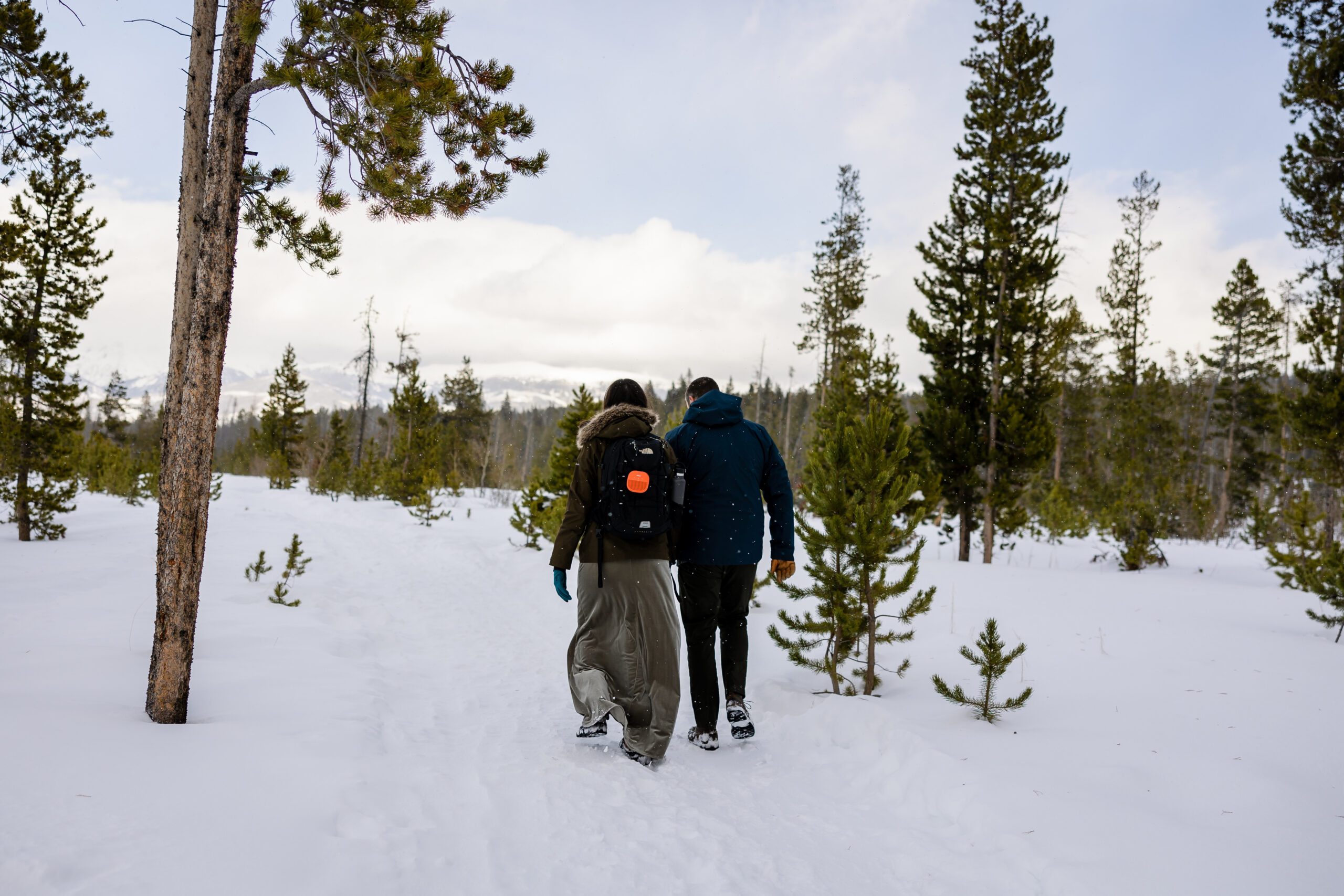 Bride and groom walking in the snow at their winter park elopement. 
