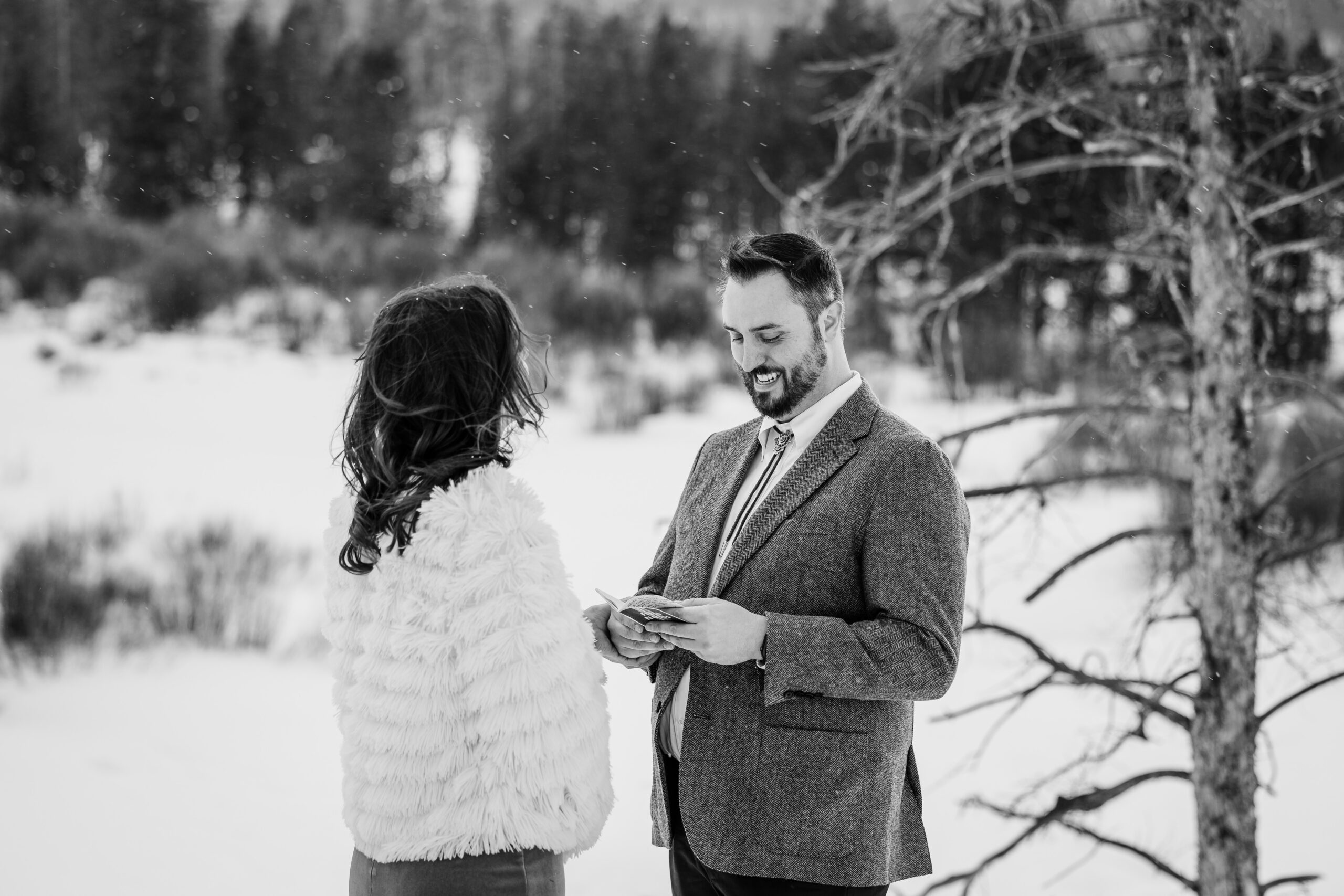 a black and white shot of the groom smiling while reading his vows during their Winter Park elopement ceremony. 