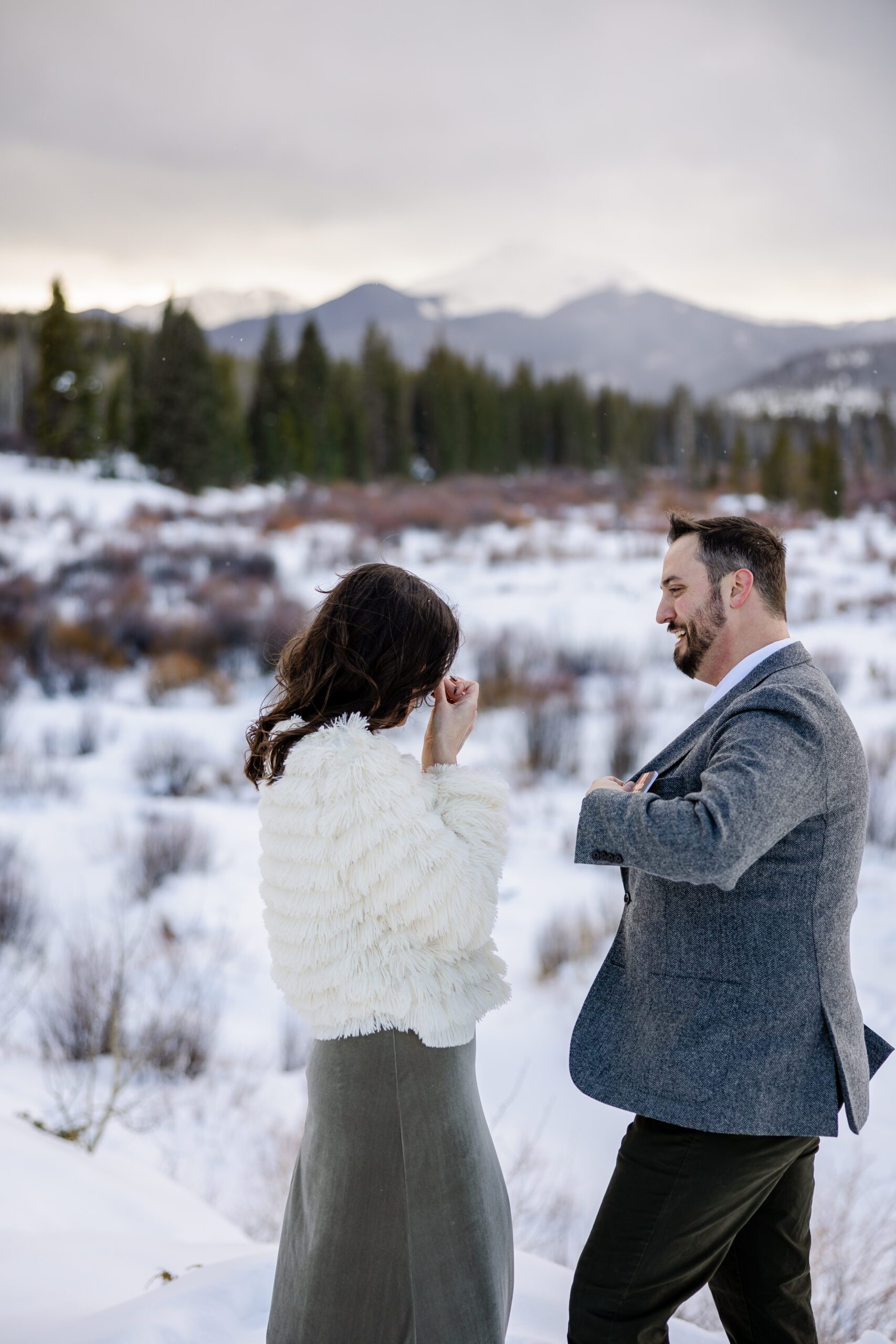The bride wiping her tears, her husband looks at her smiling, pulling his vow book out of his pocket during their Winter Park elopement ceremony. 