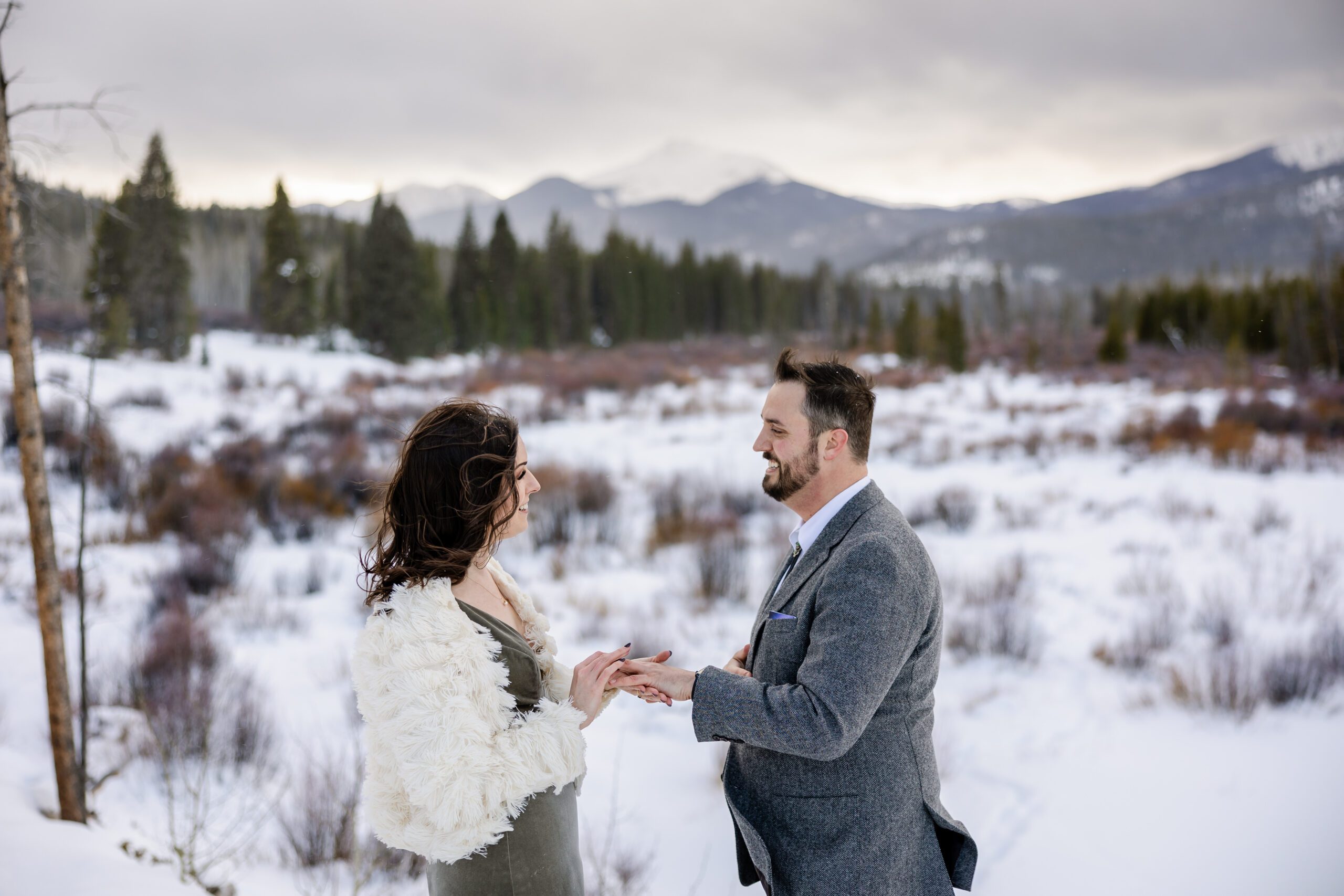 the bride putting a ring on her grooms finger, he is smiling at her during their Winter Park elopement ceremony. 