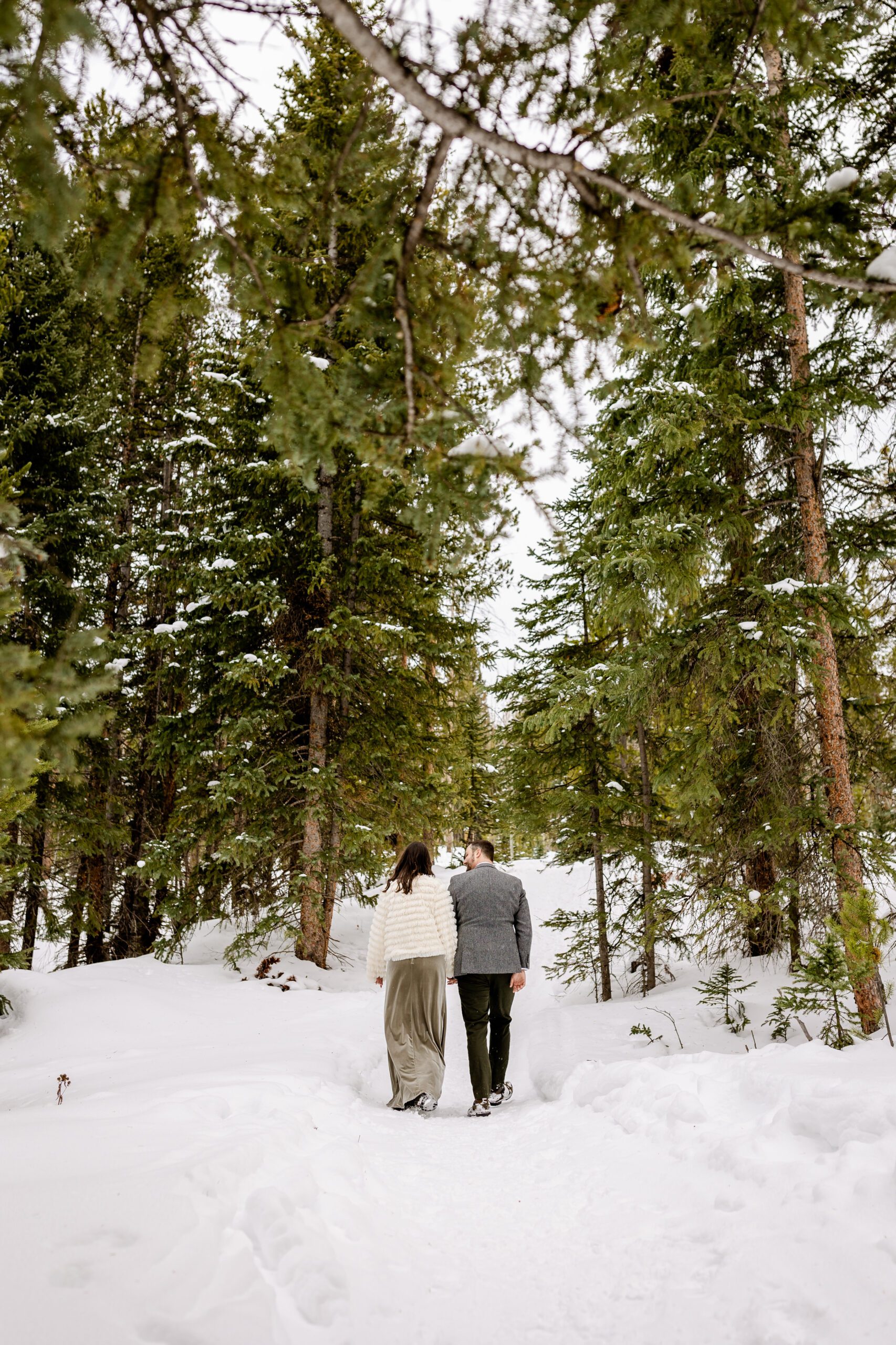 bride and groom walking in the snow at their Winter Park elopement.