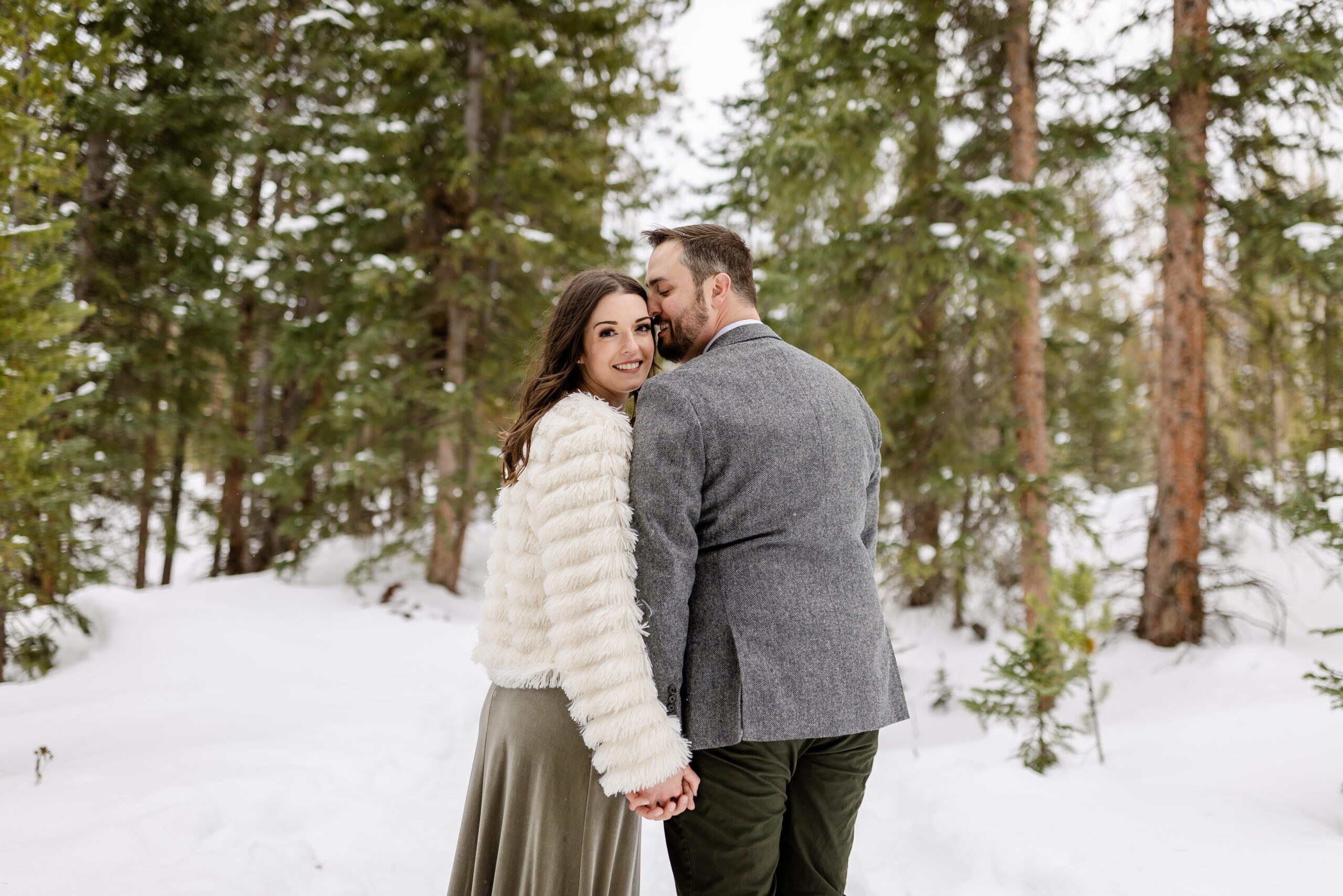 bride smiling at the camera the groom kisses her sweetly on the cheek, at their Winter Park elopement.