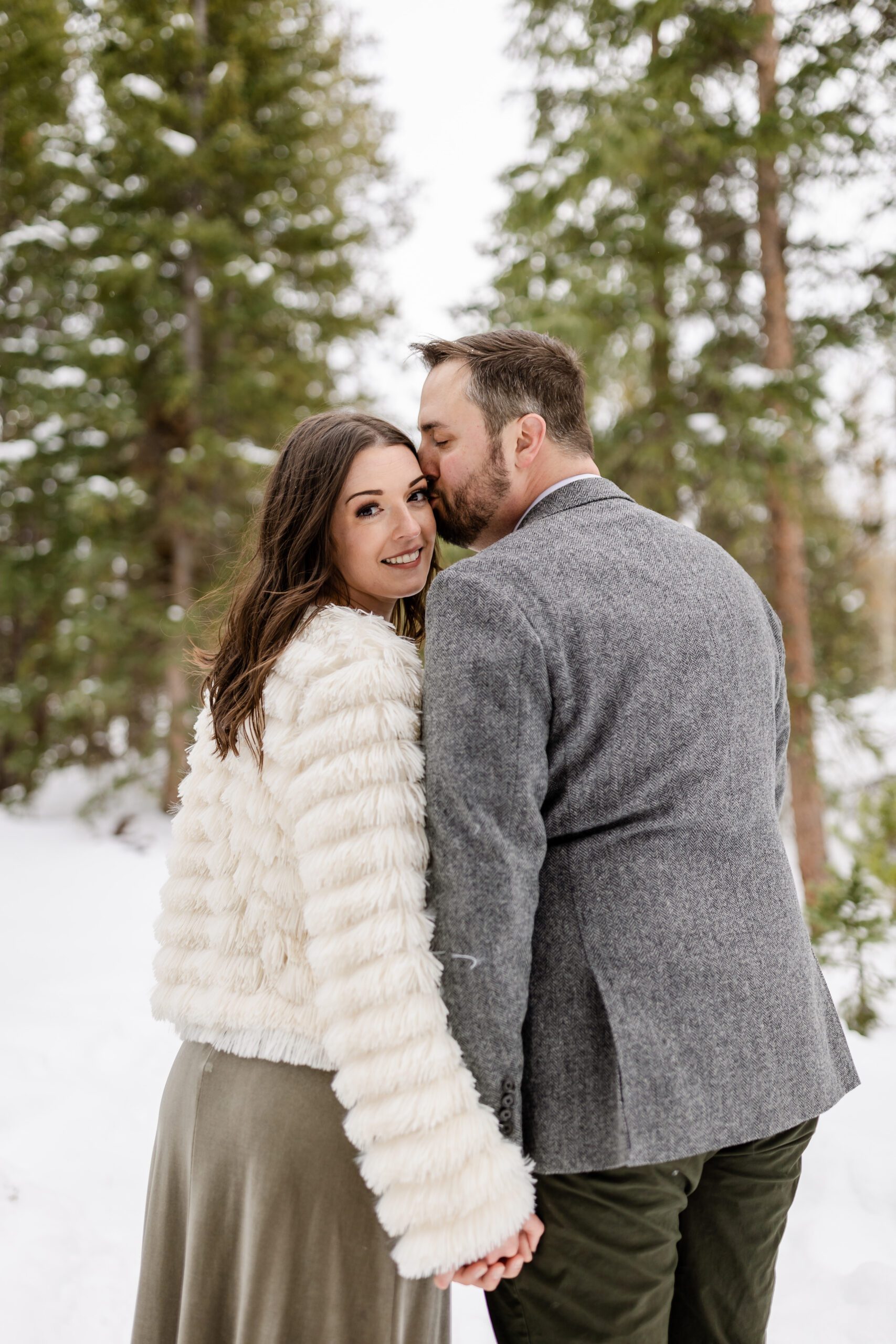 the bride smiles at the camera,  the groom kisses her on the cheek at their Winter Park elopement.