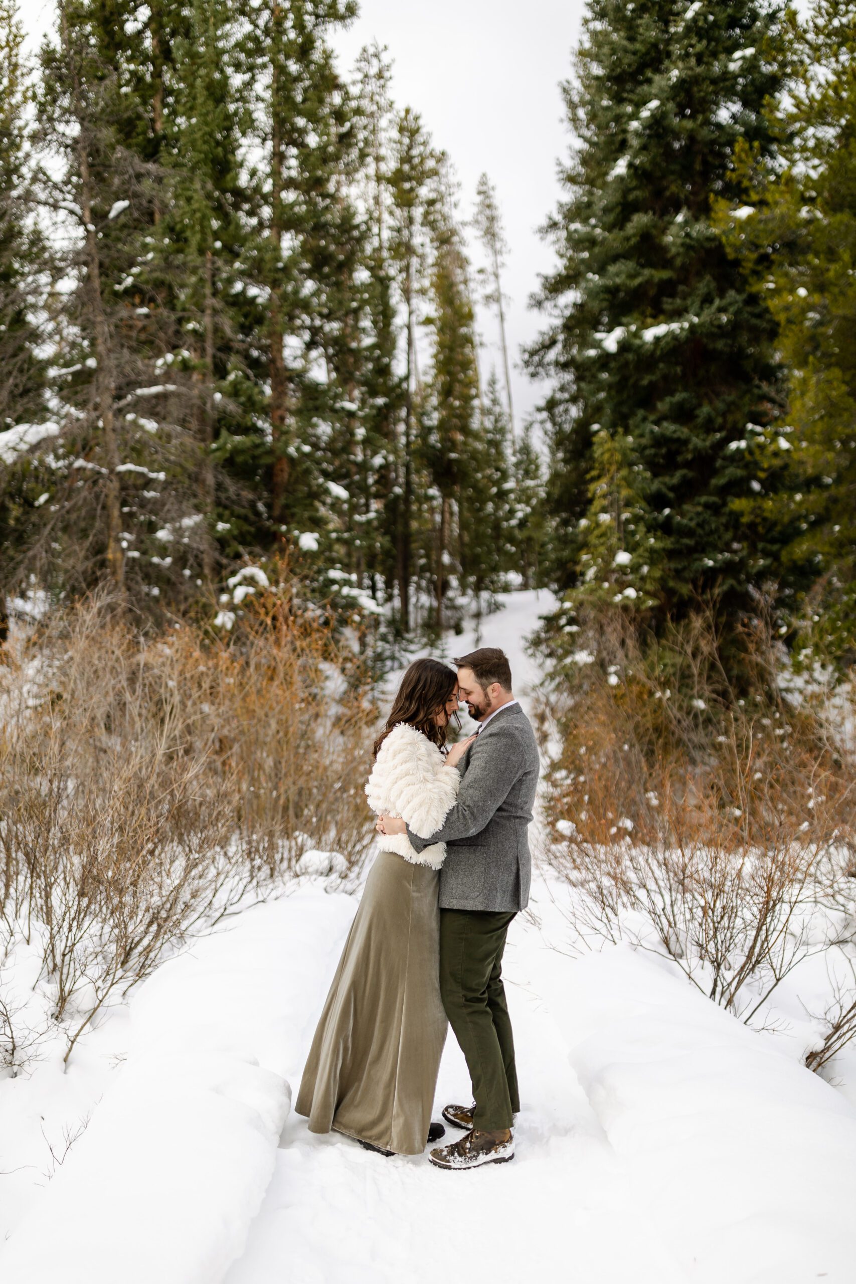 the bride and groom smiling cuddling in the snow at their Winter Park elopement.
