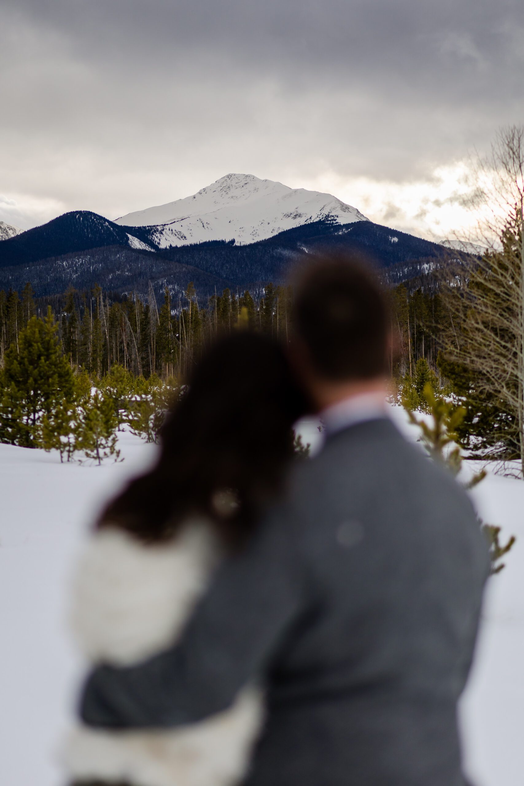 an out of focus shot of the couple with an in focus mountain shot at their Winter Park elopement.