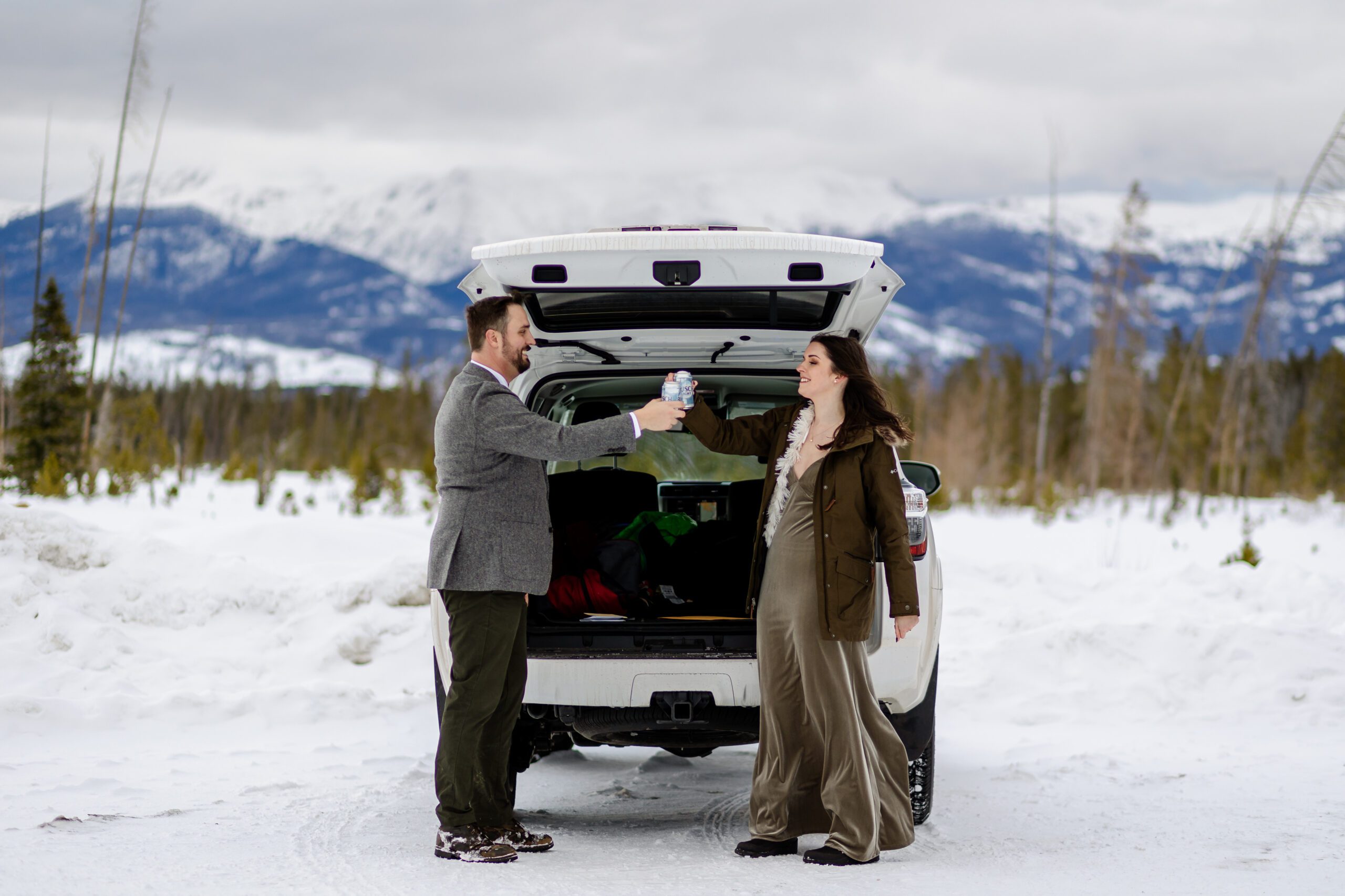 the bride and groom cheers with a beer after their  Winter Park elopement in front of their car. 