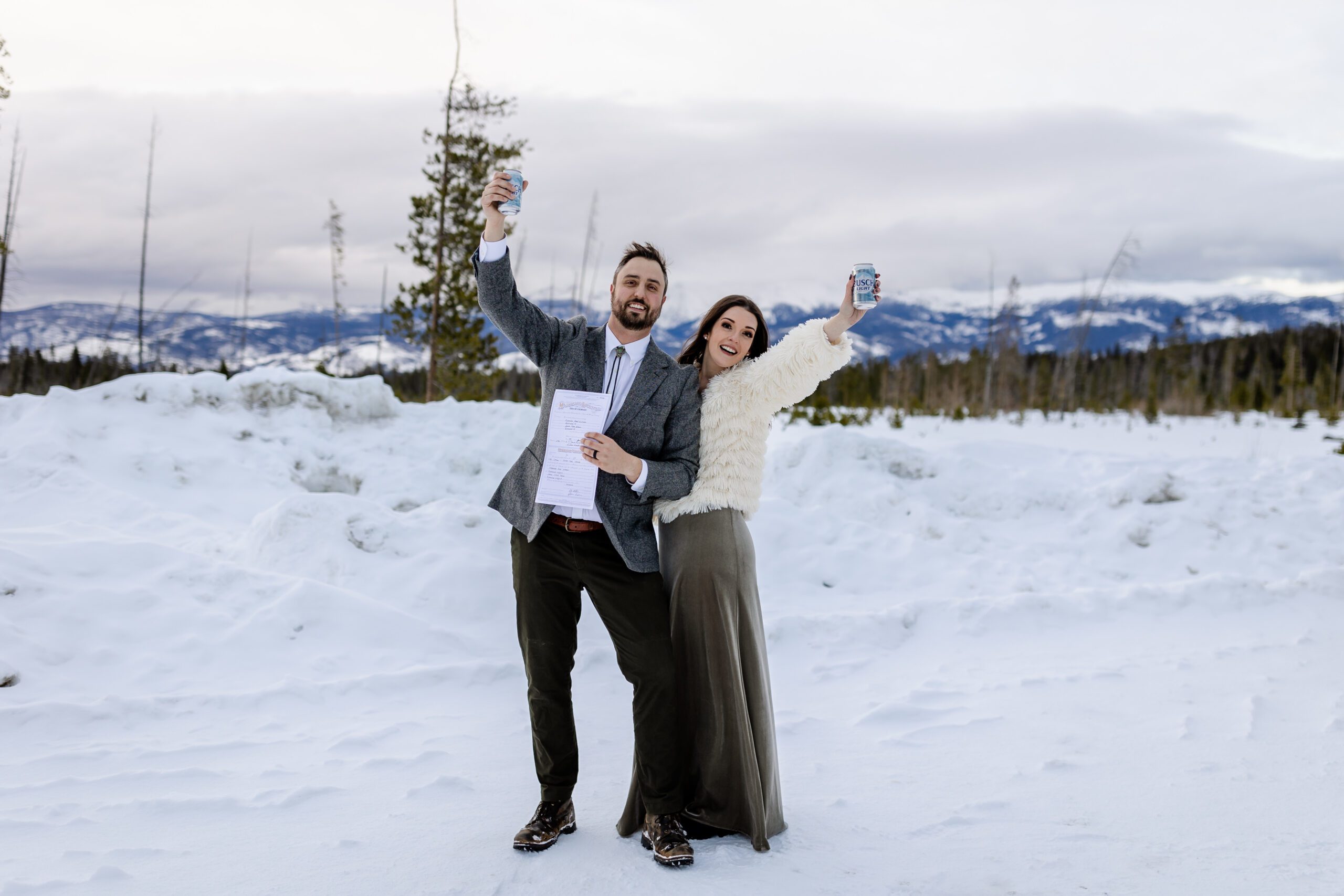 bride and groom holding beer up in the air, after their Winter Park elopement.