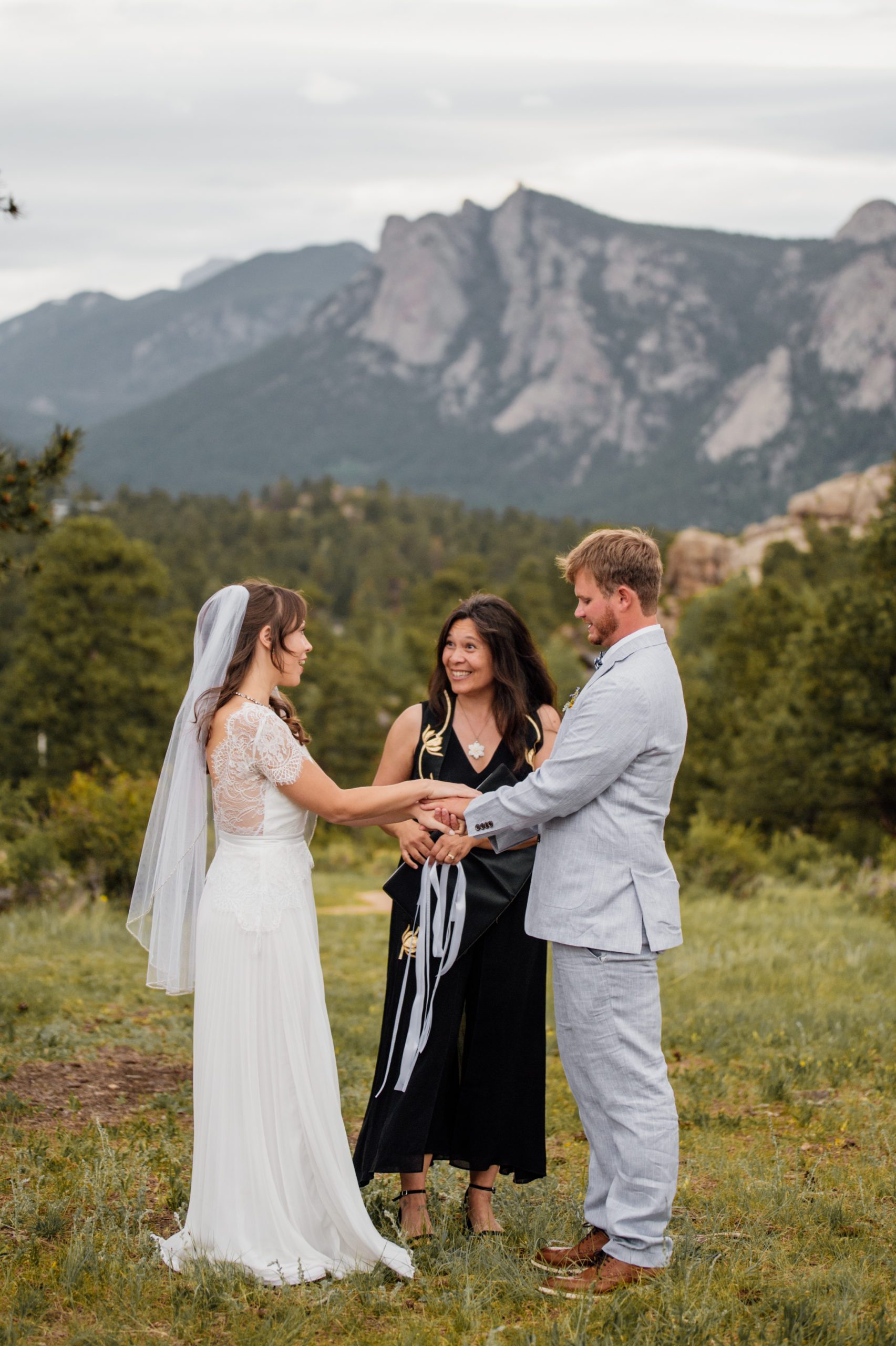 The bride and groom hold hands during their hand-fasting ceremony at Knoll Willows for their elopement in Estes Park.