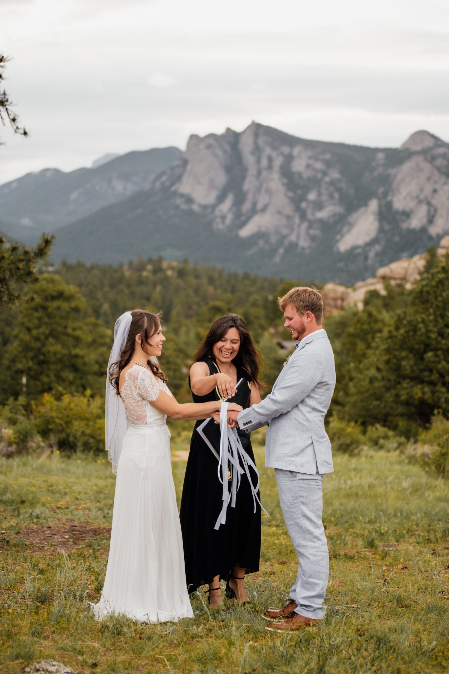 The bride and groom laughing during their hand fasting ceremony during their elopement at  Knoll Willows in Estes Park.