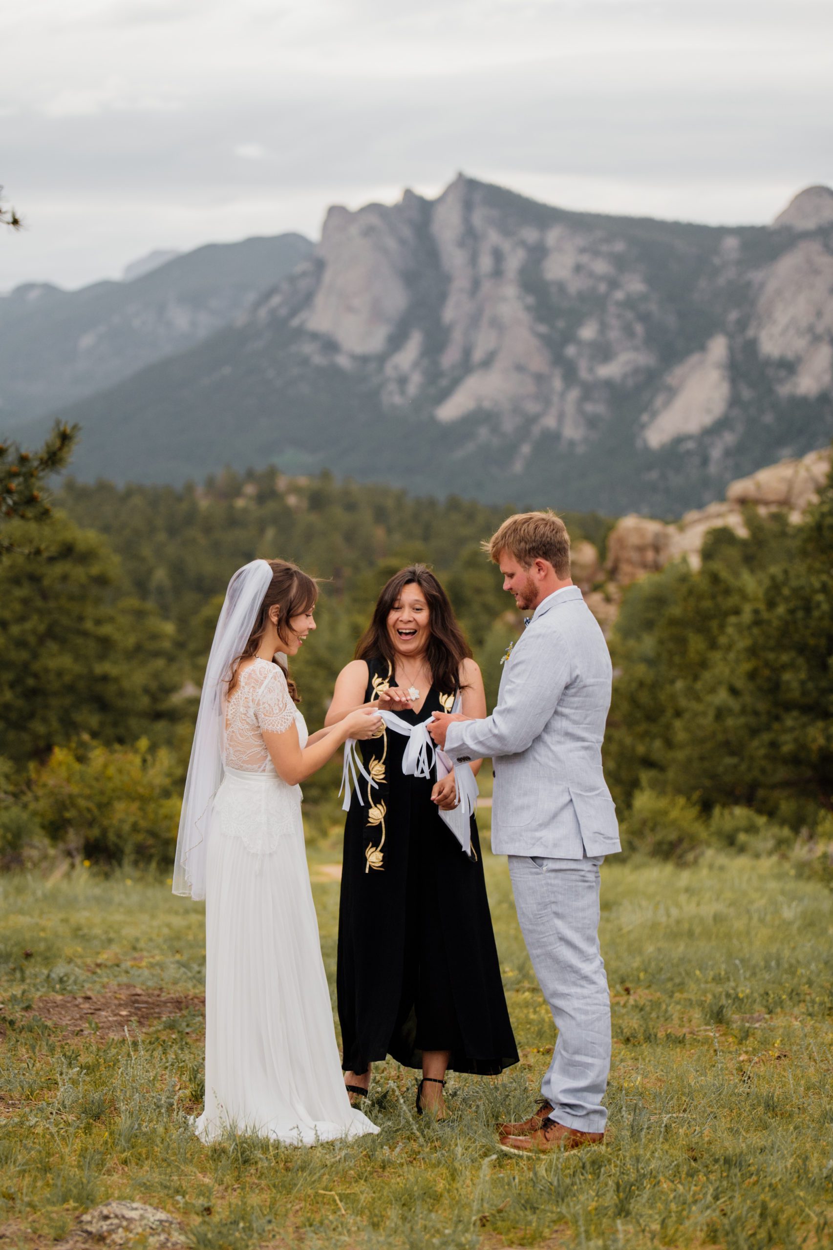 The officiant, bride and groom giggle during their elopement ceremony at Knoll Willows in Estes Park.