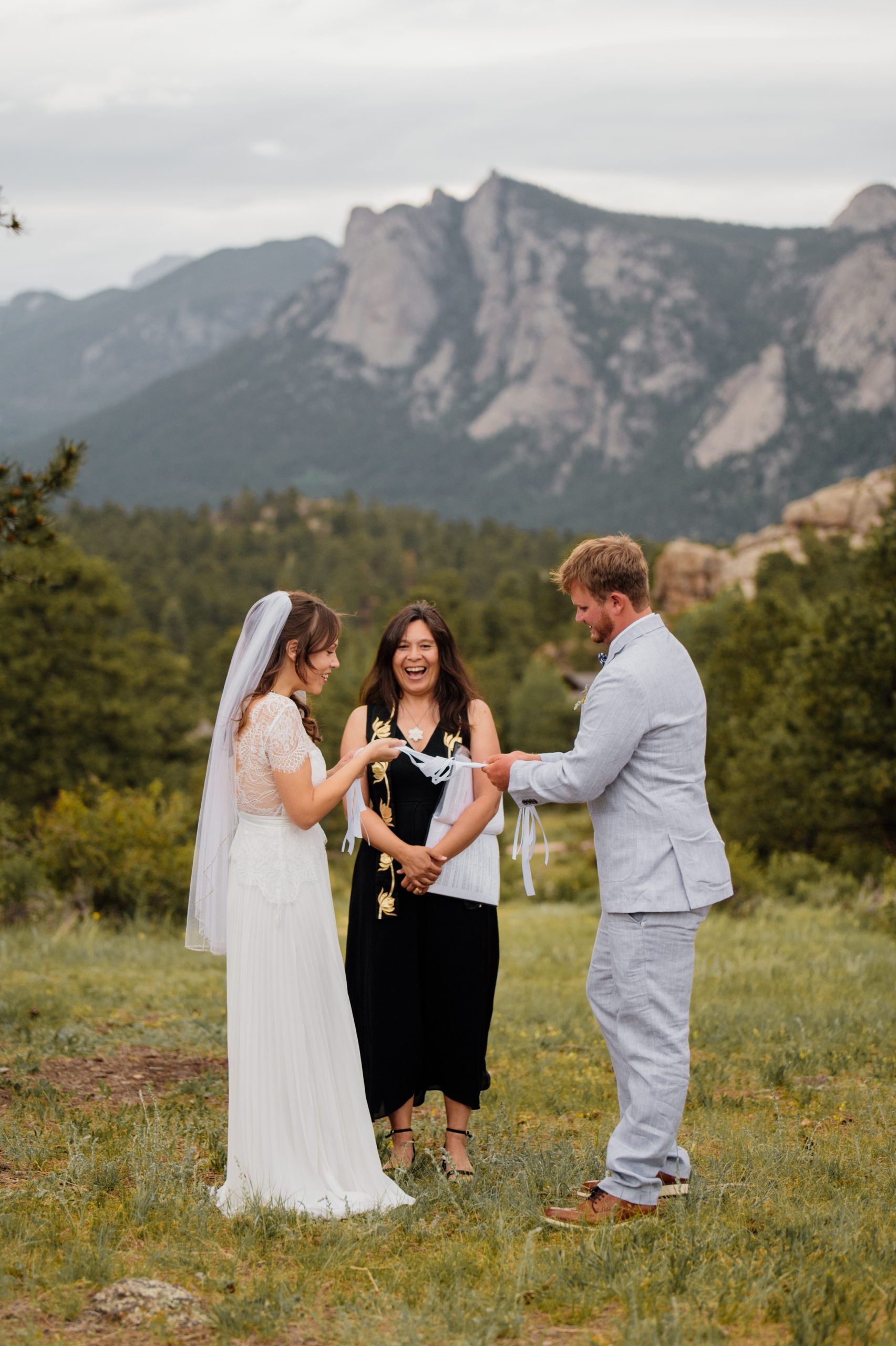 The next step in the hand-fasting ceremony for the bride and groom during their elopement ceremony at Knoll Willows in Estes Park.