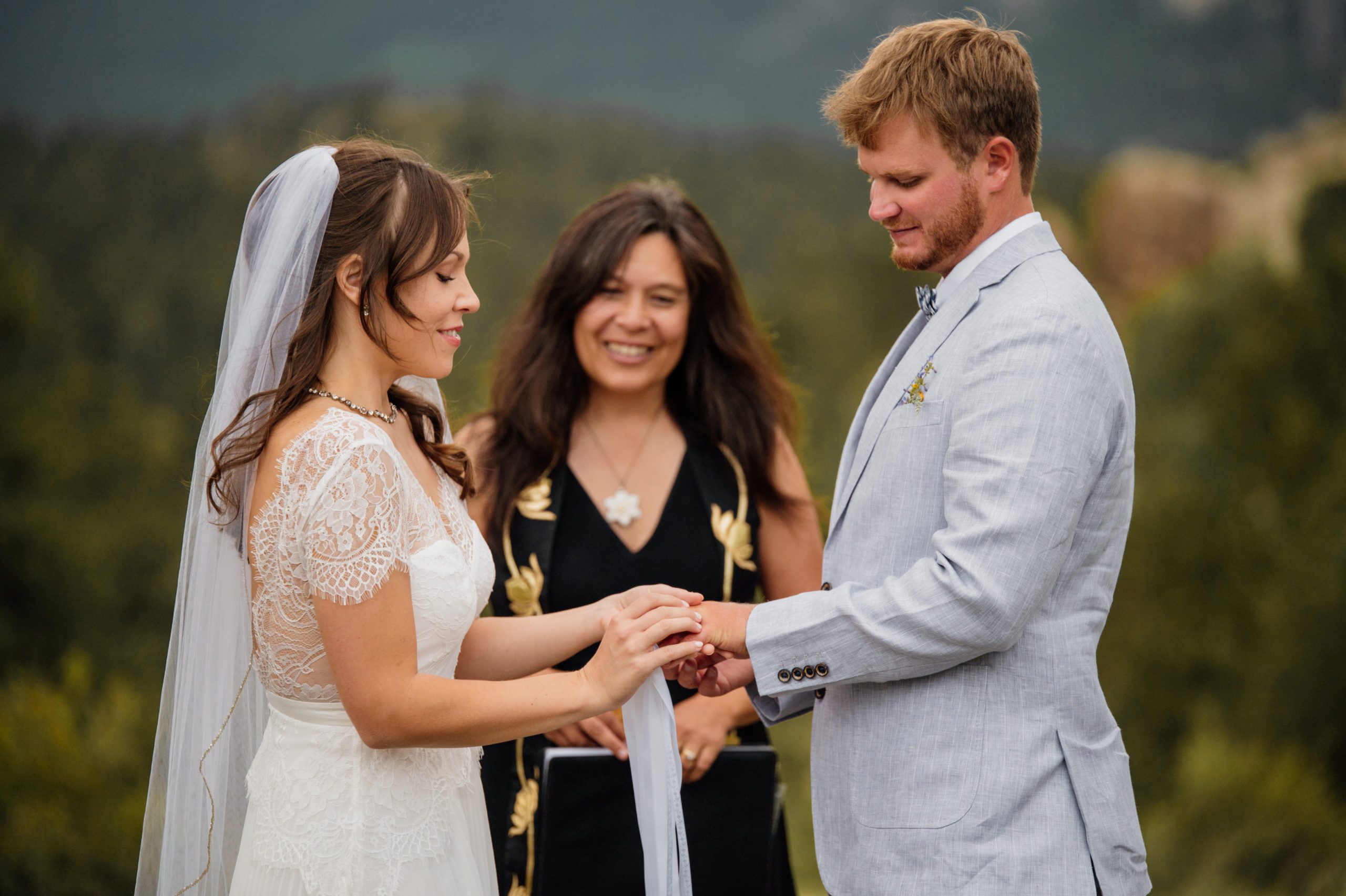The bride places the ring on her husbands hand during their their elopement ceremony at Knoll Willows in Estes Park.