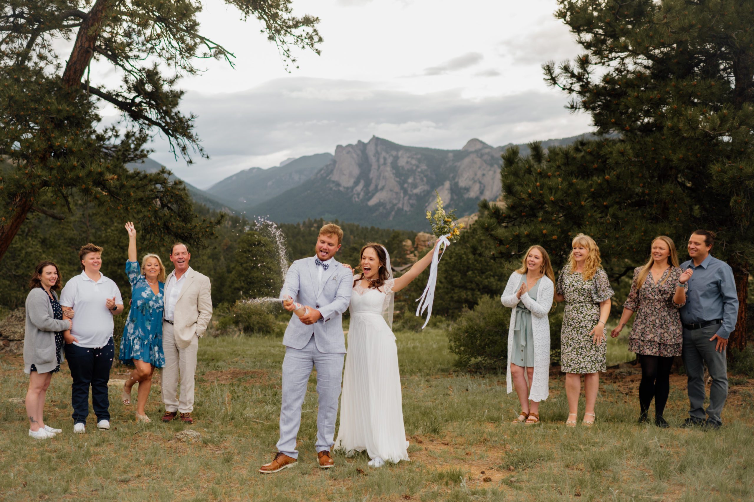 The bride and groom pop a bottle of champagne after their elopement ceremony at Knoll Willows in Estes Park.