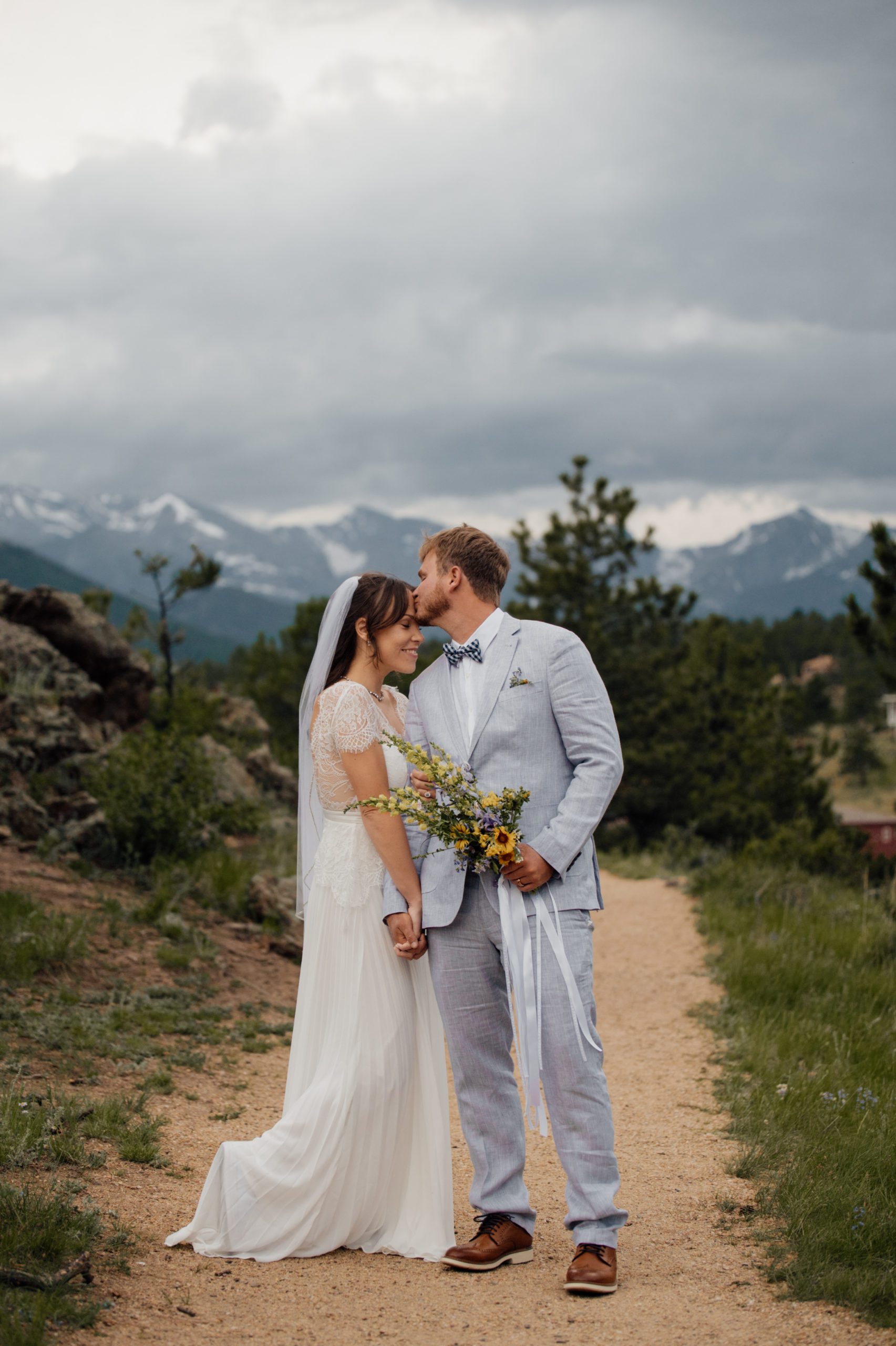The groom gently kisses his brides forehead after their elopement at Knoll Willows in Estes Park. 