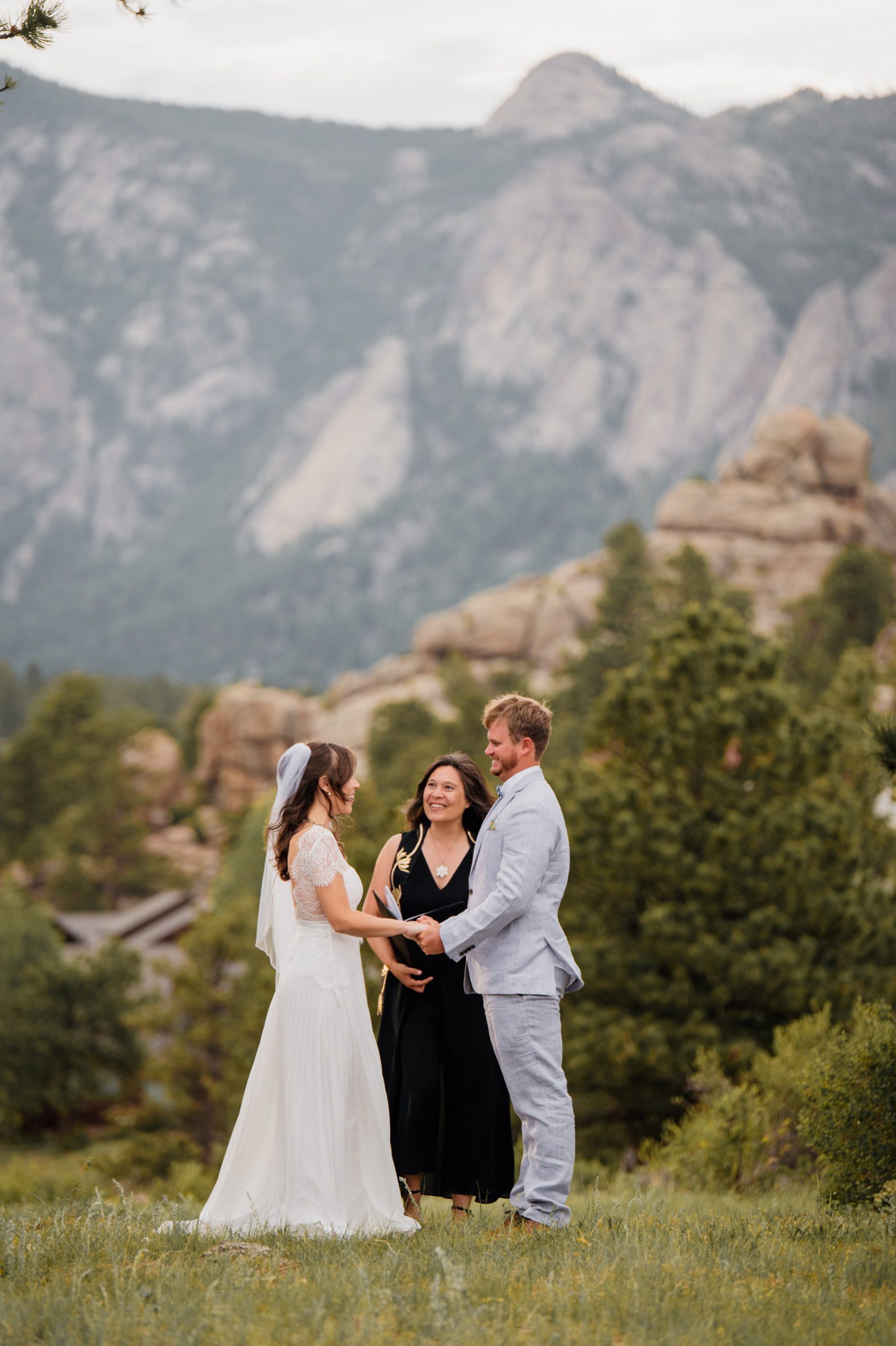 The bride and groom hold hands at the beginning of their Knoll Willows ceremony at Estes Park. 