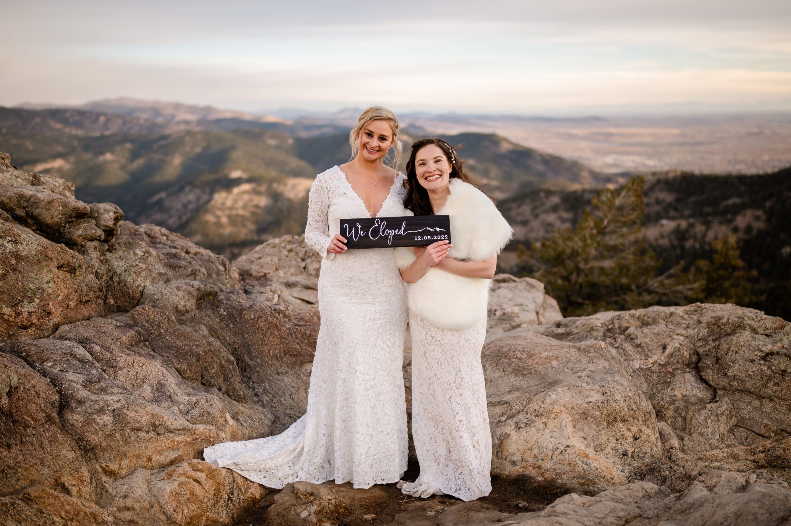 The brides hold a "we eloped" sign at their Lost Gulch elopement. 