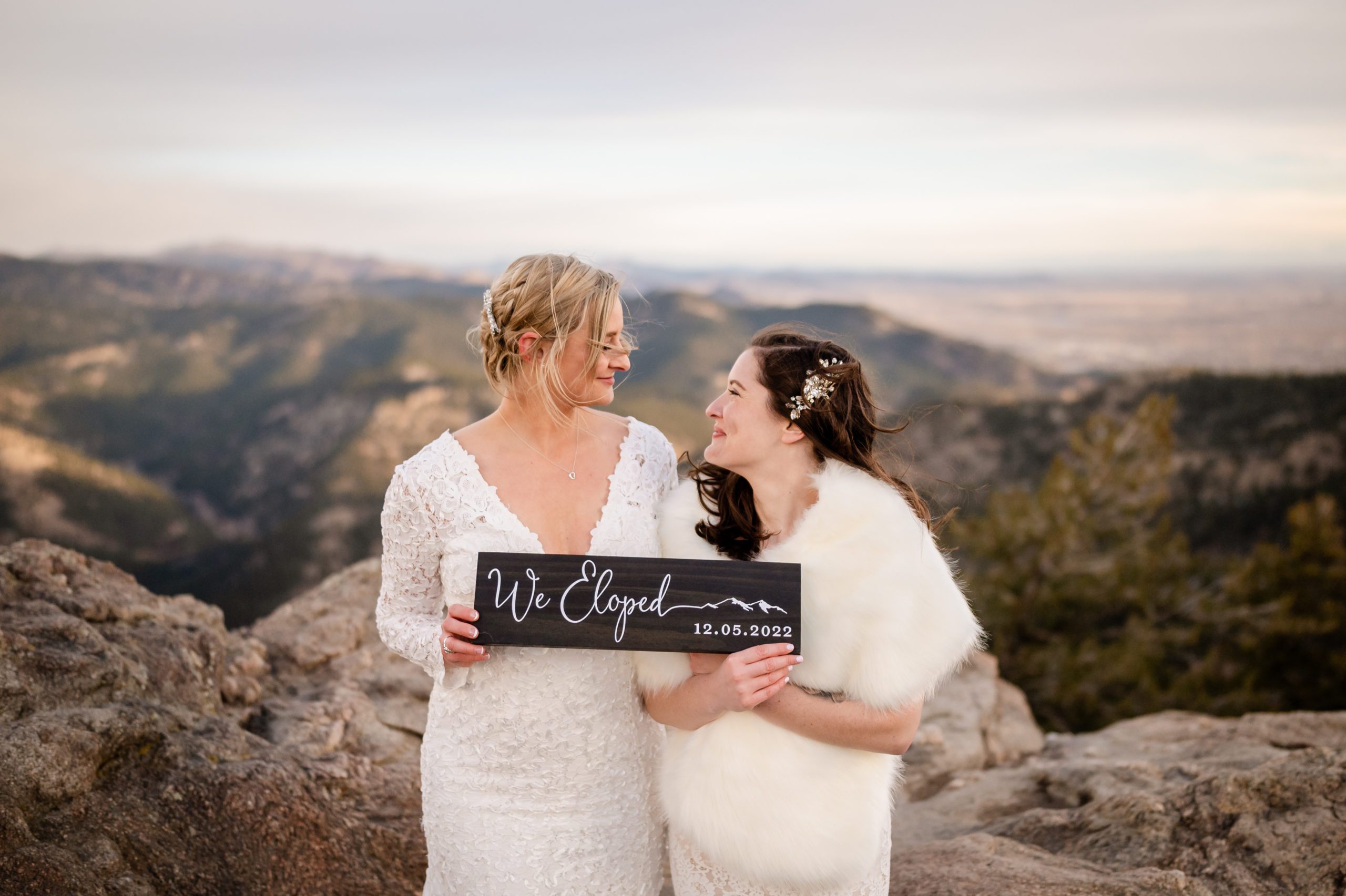 The bride's look at each other while holding their "We eloped" sign at their Lost Gulch elopement. 