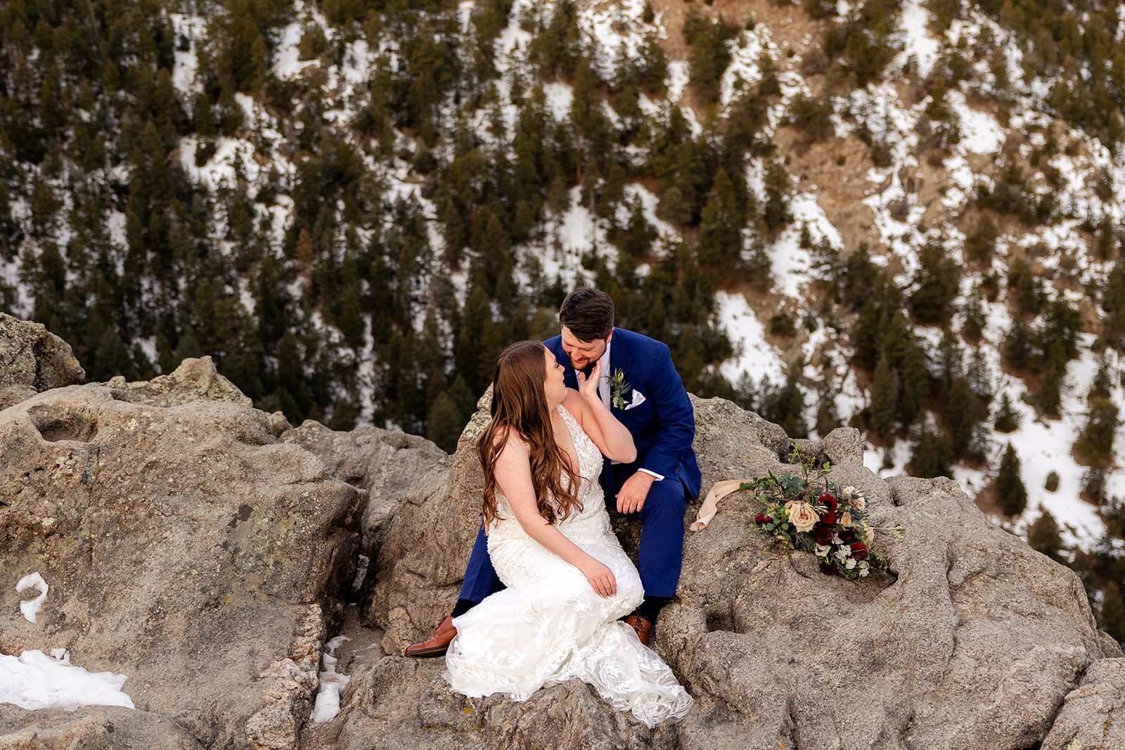 Bride sits on the Lost Gulch overlook while kissing her groom during their Lost Gulch elopement with  videography.