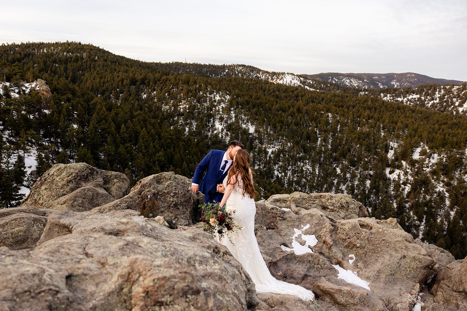 The groom leans down to kiss his bride on top of Lost Gulch during their Lost Gulch elopement with  videography.
