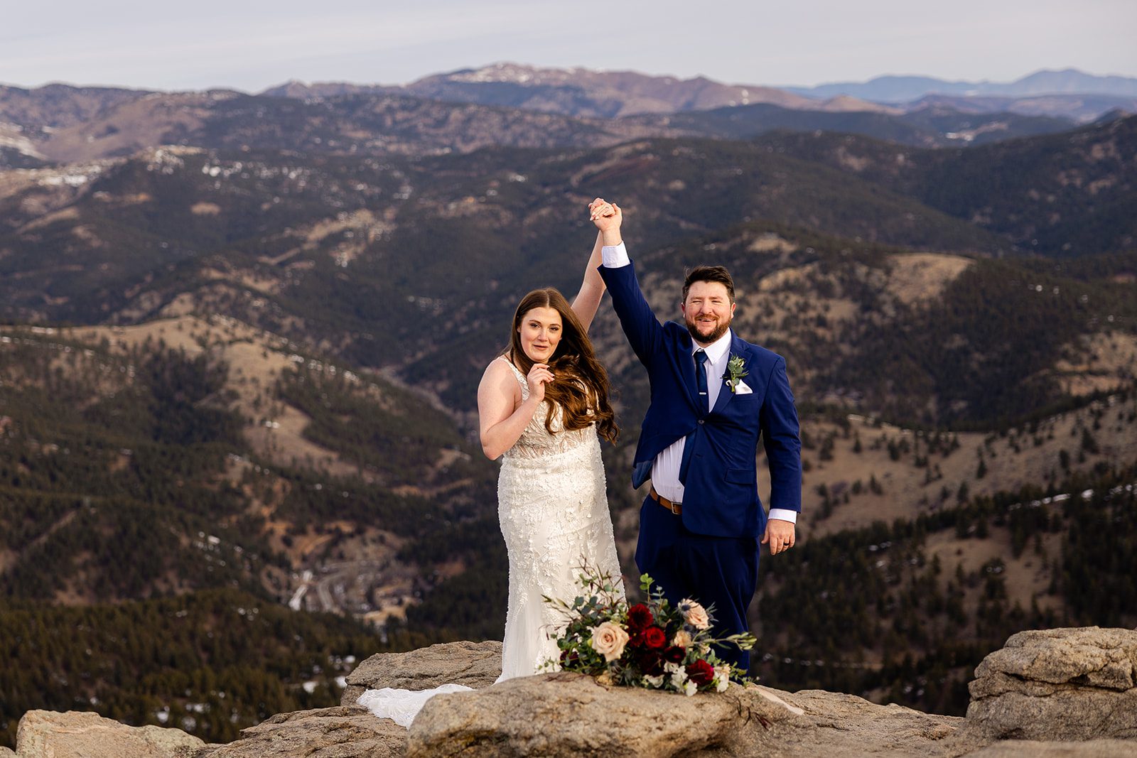 Bride and groom raise their hands in celebration after their Lost Gulch elopement with  videography.