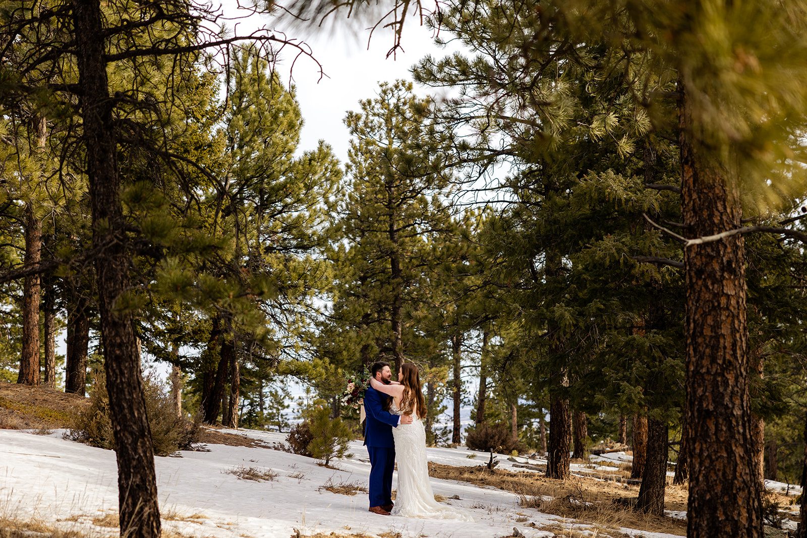 bride and groom holding each other in the snow at their Lost Gulch elopement with  videography.