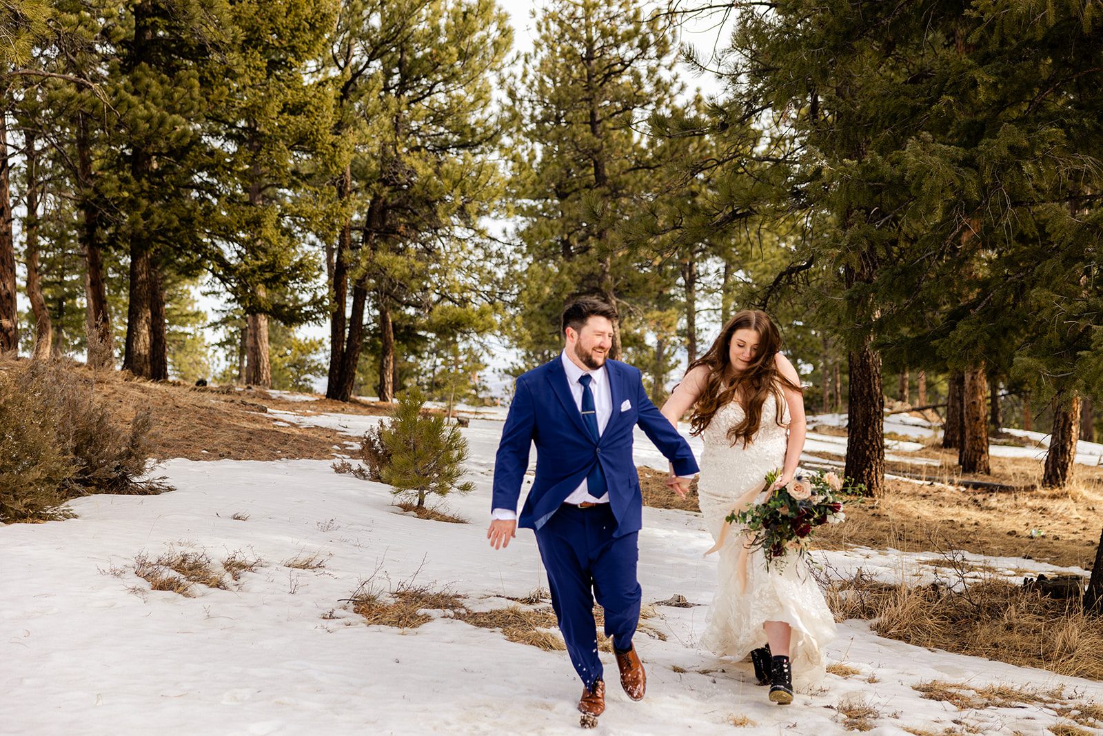 groom and bride running in the snow after their Lost Gulch elopement with  videography.