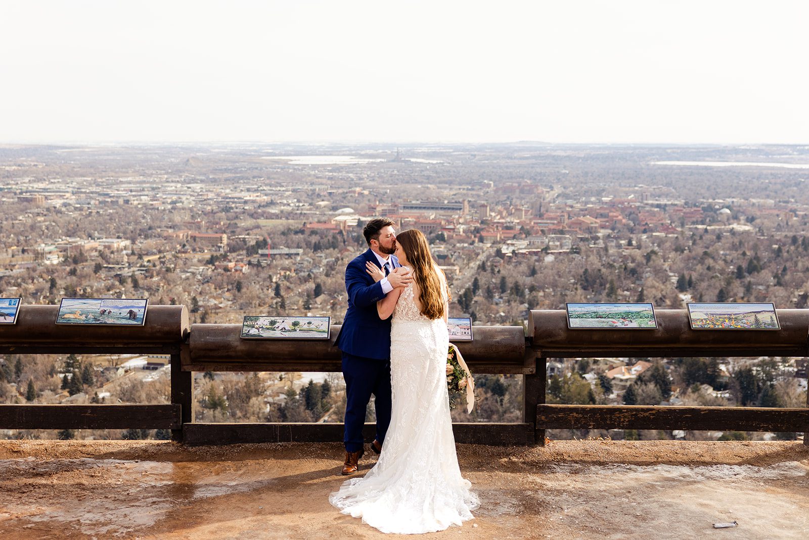 groom kisses bride with the city behind them afte their Lost Gulch elopement with  videography.