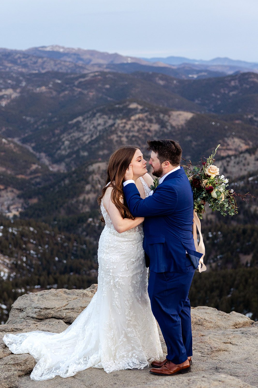 Groom holds his bride's face on top of Lost Gulch during their elopement with videography.