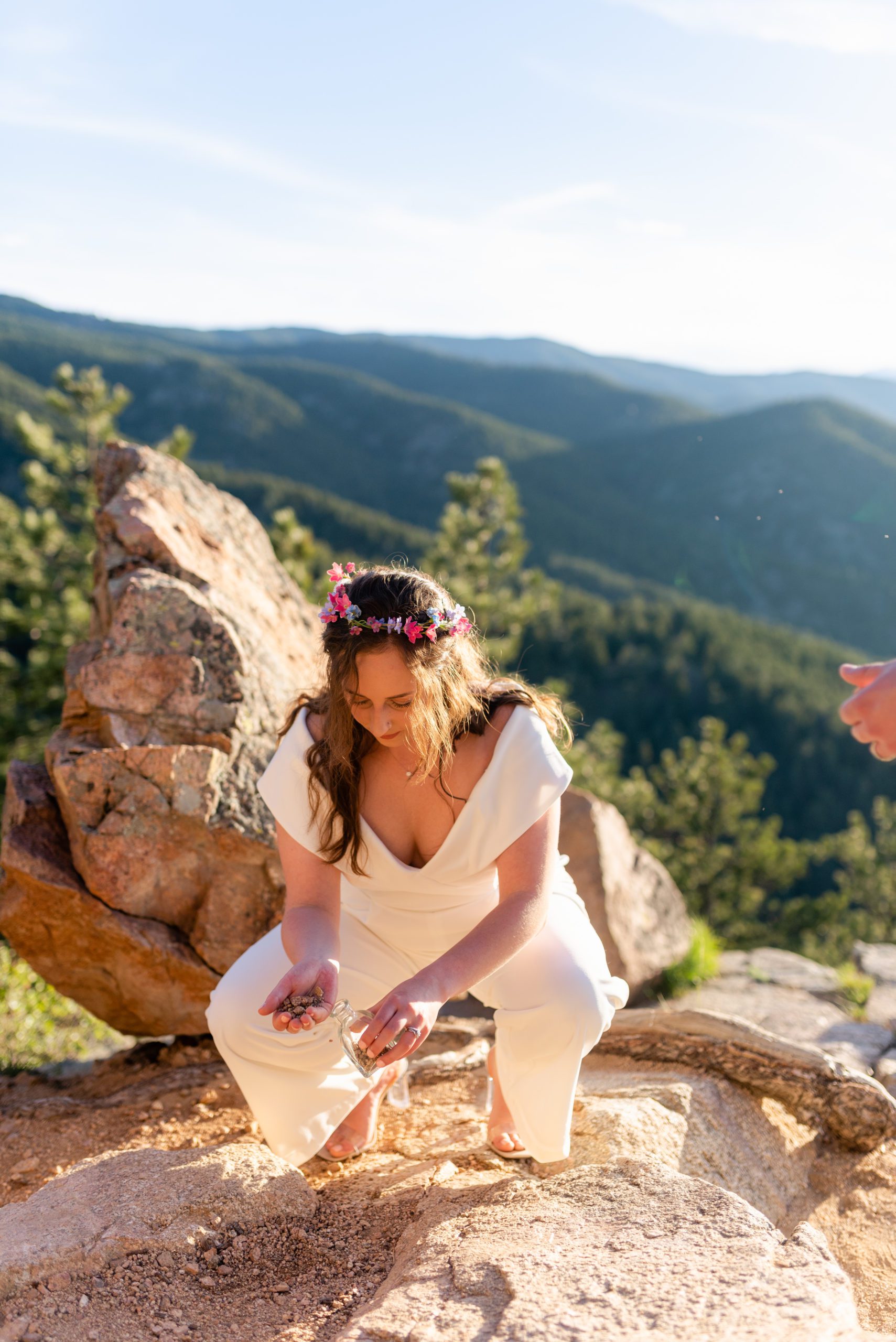 The bride pouring a handful of rocks into her keepsake  jar during their Boulder Hiking elopement near Realization point. 