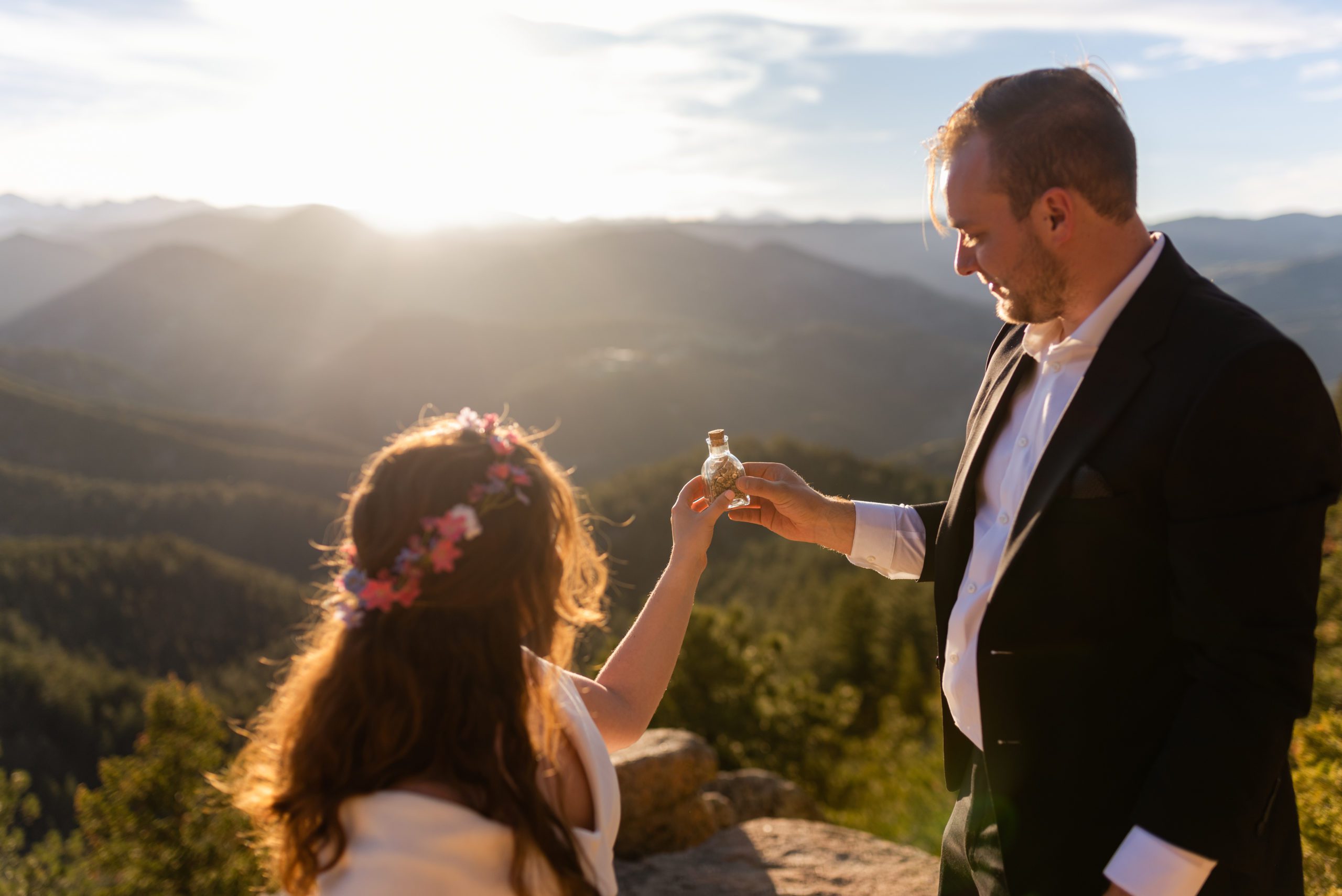 The bride and groom hold their keepsake jar of pebbles into the sunset at their Boulder Hiking elopement near Realization point. 