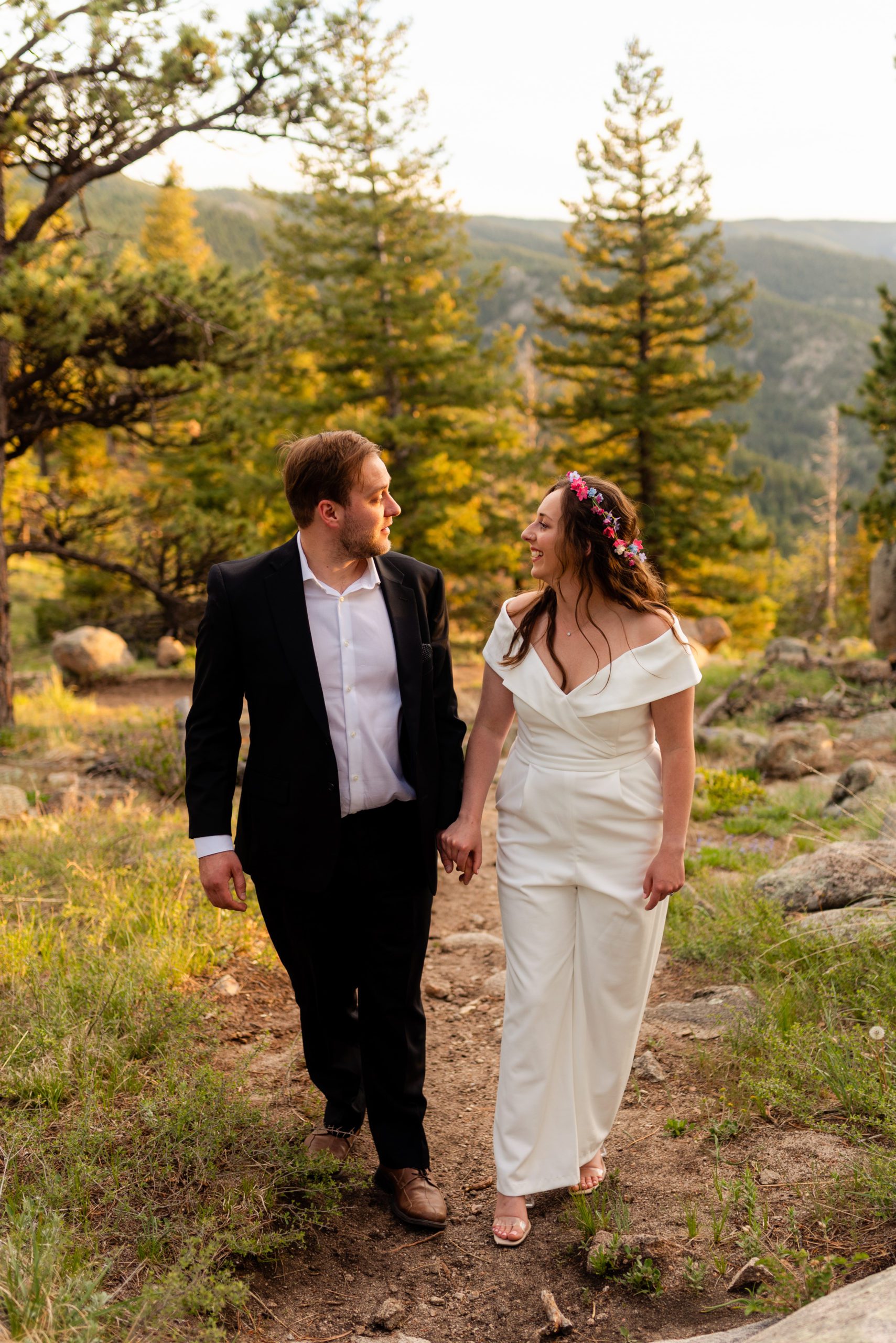 The bride and groom hand in hand walking together and smiling at each other during their Boulder Hiking elopement near Realization point. 