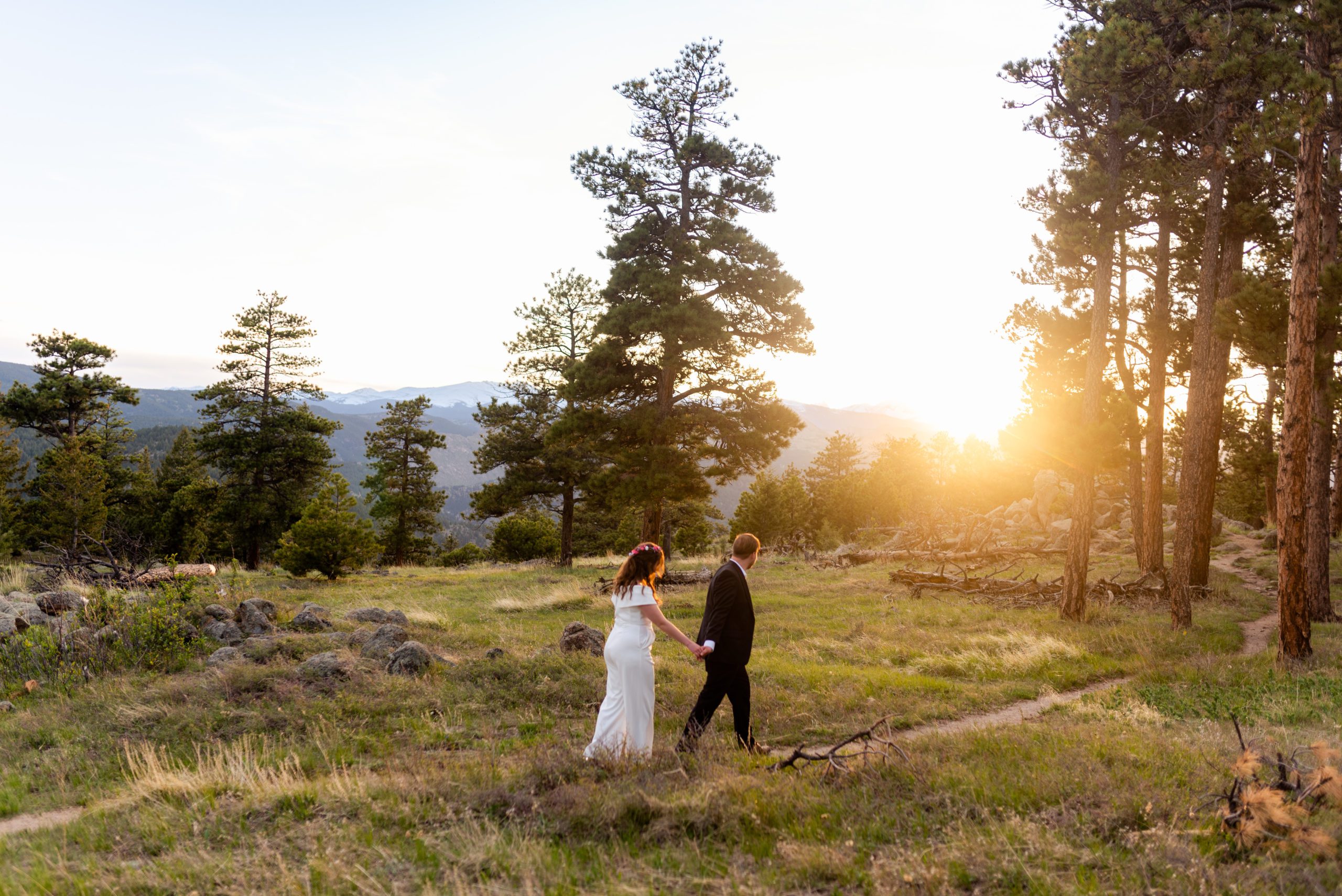 The bride and groom holding hands and walking into the sunset during their Boulder Hiking elopement near Realization point. 