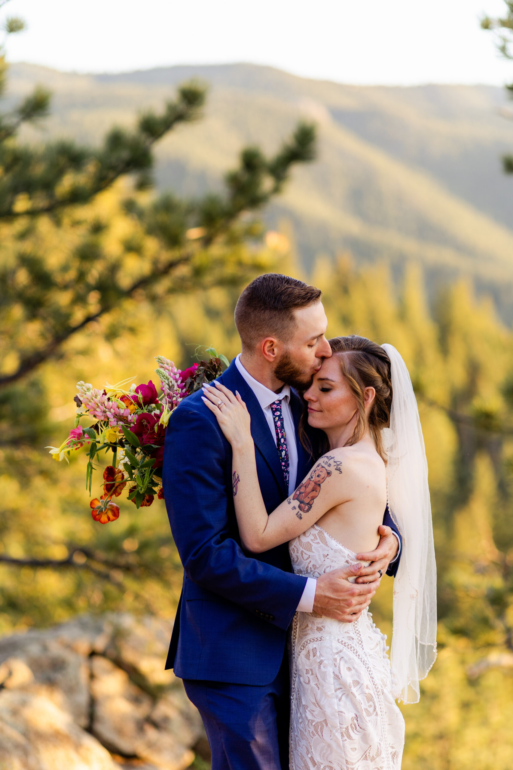 The groom kissing his bride on her should at Artist Point after their Sunrise Amphitheater elopement ceremony. 