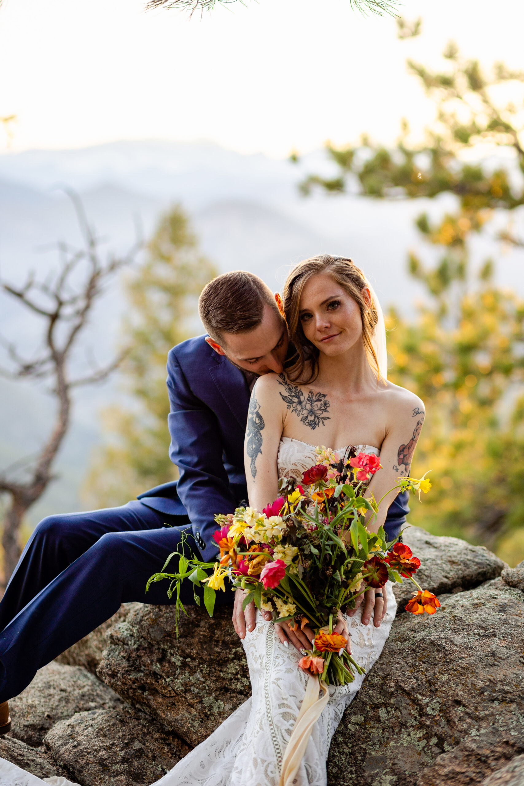 the bride looks sweetly at the camera while her groom kisses her should picnic at Artist Point after their Sunrise Amphitheater elopement ceremony. 