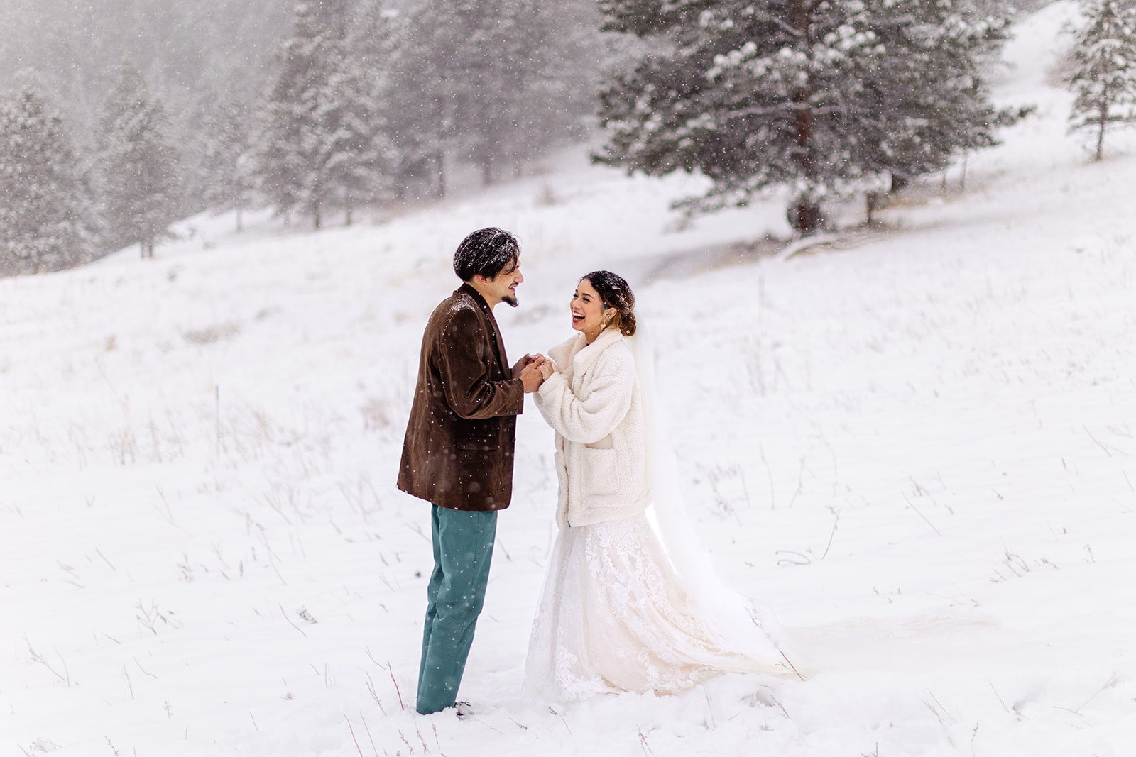 bride and groom holding hands on Flagstaff Mountain on a snowy spring day after their halfway house elopement ceremony