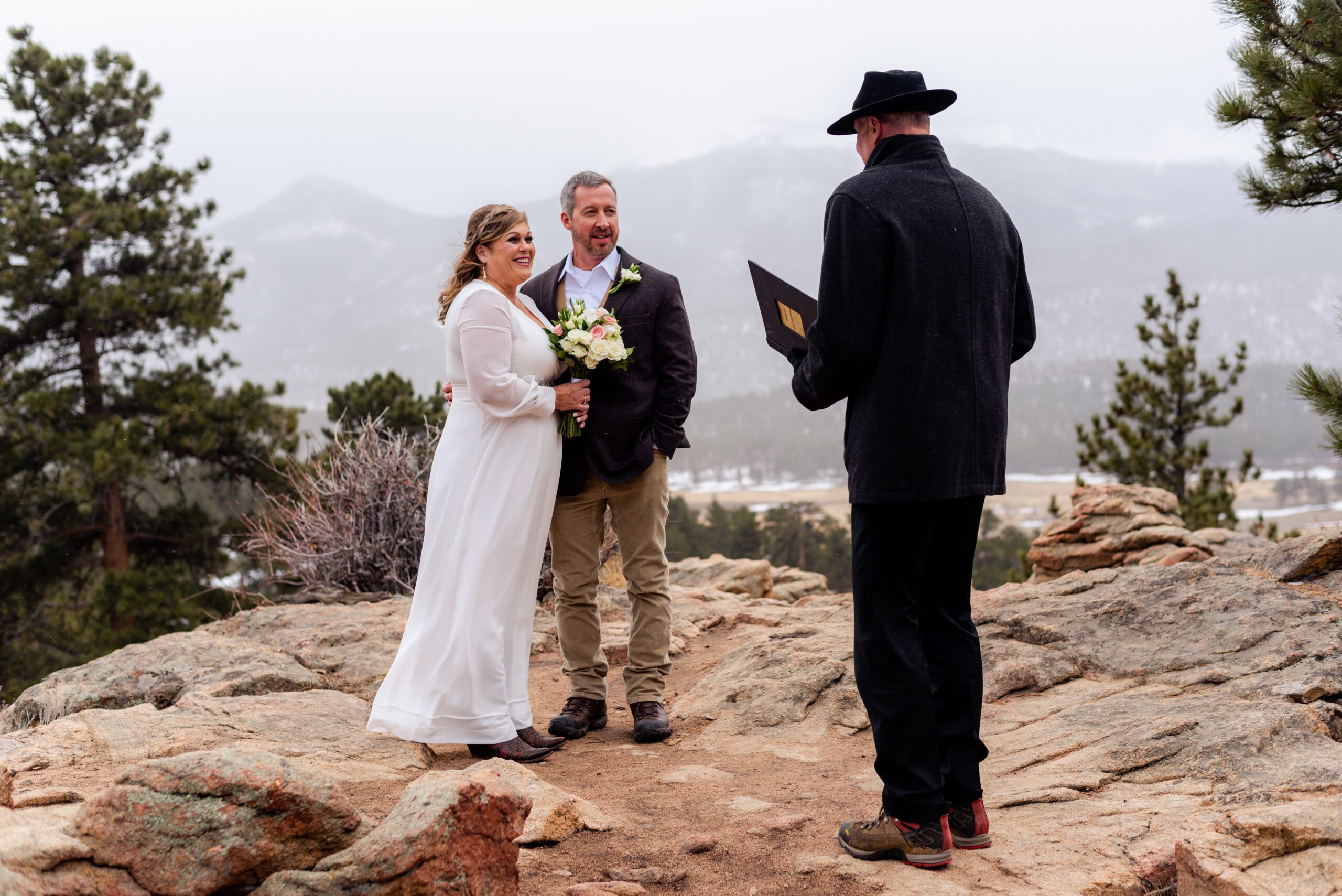 bride and groom smile sweetly at their officiant during their spring  elopement at 3M Curve in Estes Park.