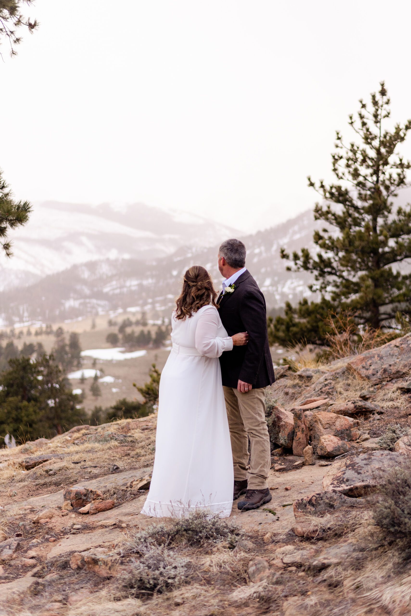 the bride and groom look out on the snowy mountain top during their spring elopement at 3M Curve.