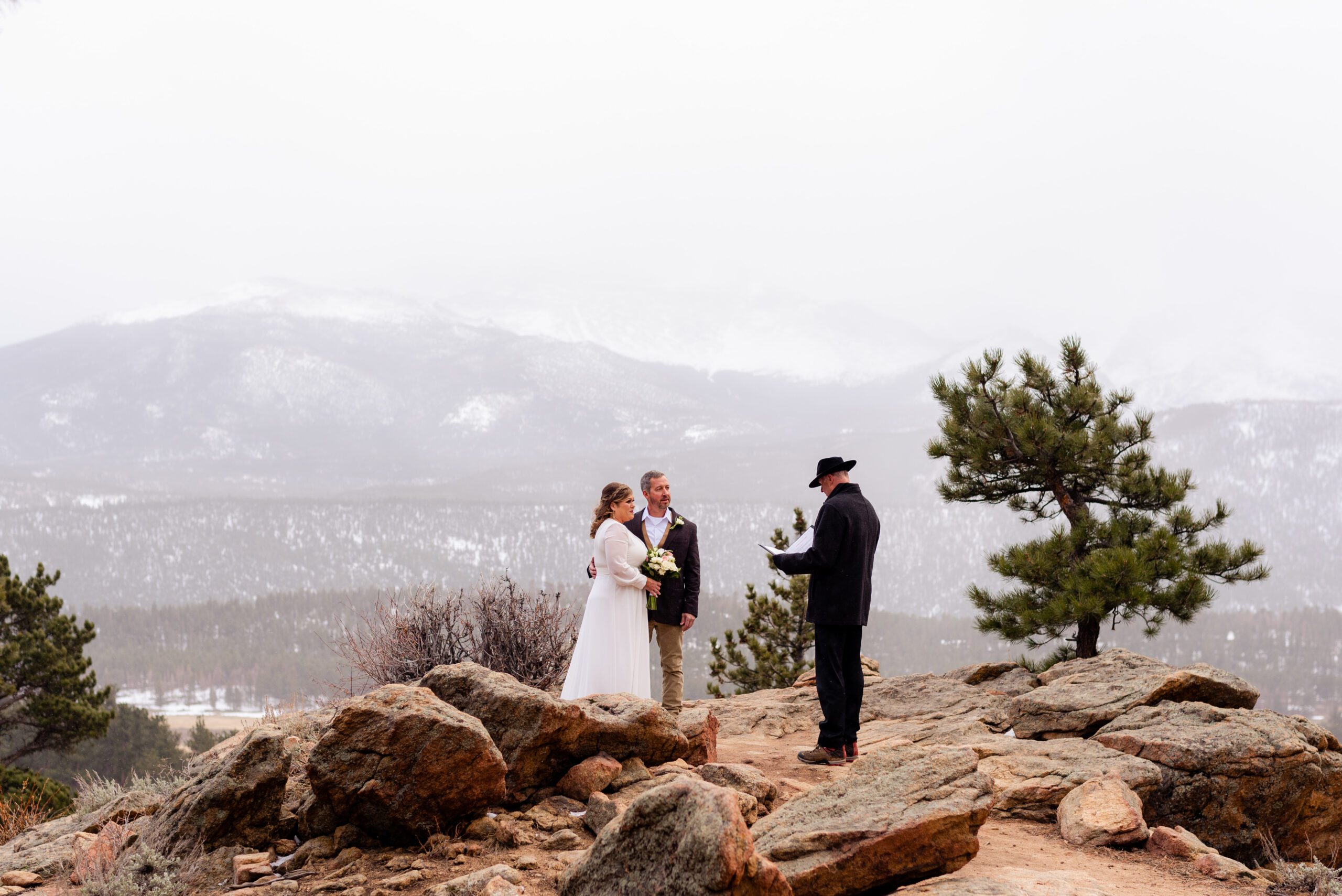 the snowy-white mountains in the distance, the bride and groom listen to the officiant during their spring elopement at 3M Curve.